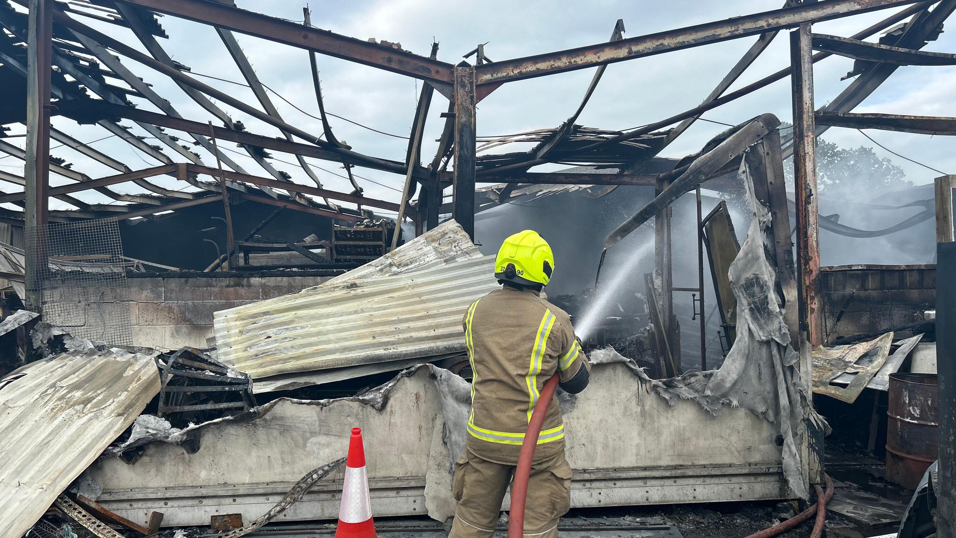 A firefighter seen from the back with a burned out building in front of them