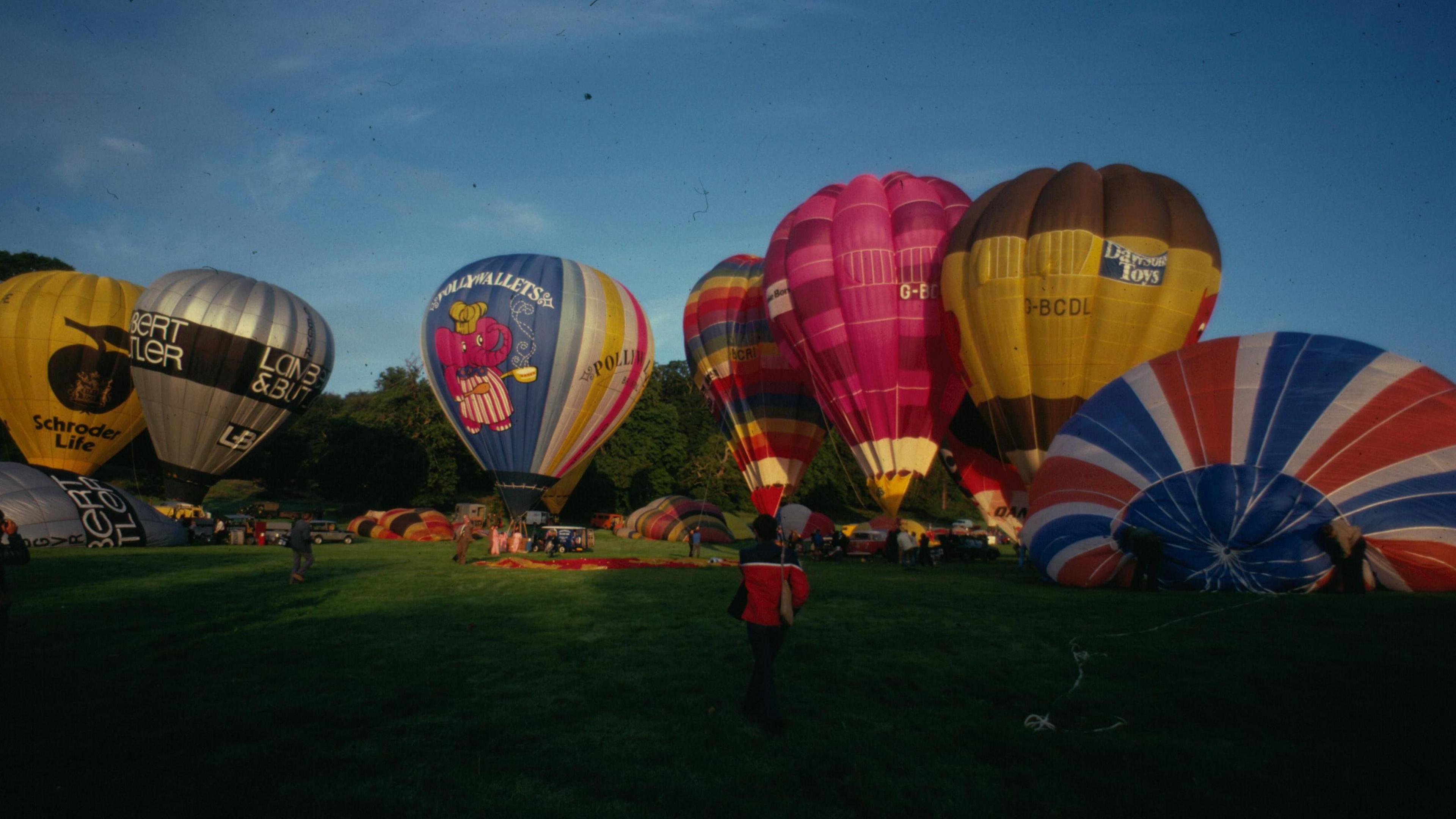 Hot air balloons inflated but still tethered resting near the ground