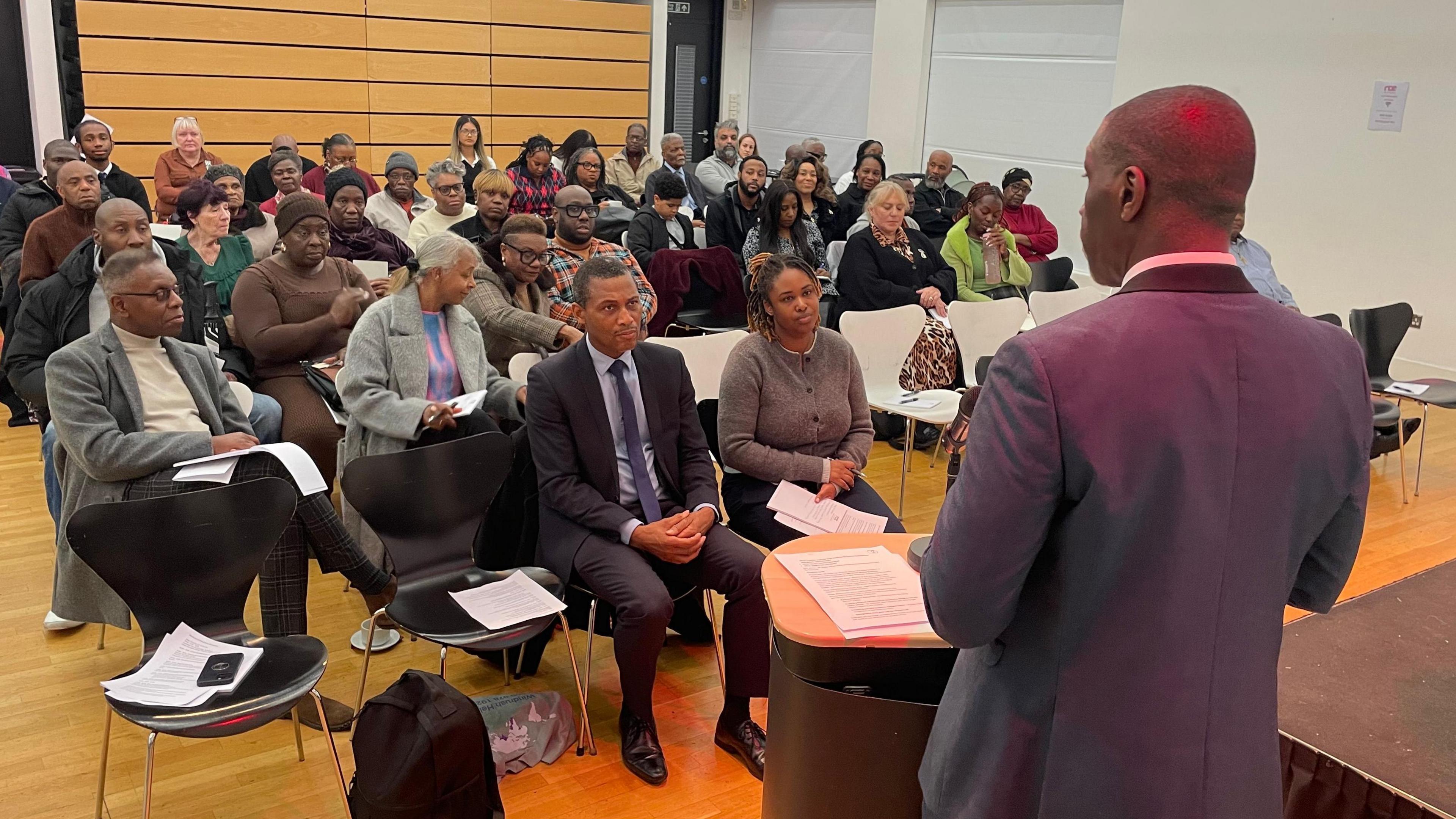 Rev Foster is standing at a podium speaking to people who attended his Nottingham event