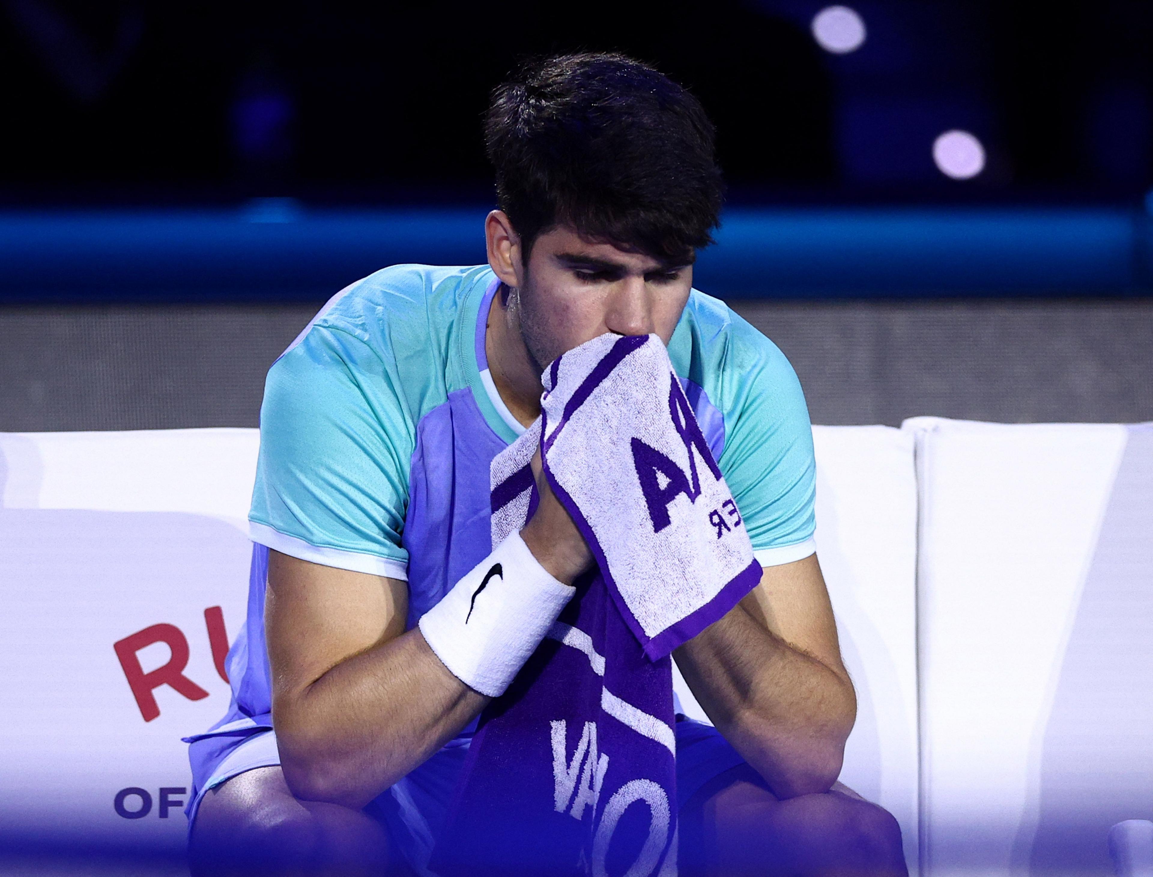 Carlos Alcaraz looks dejected as he uses a towel