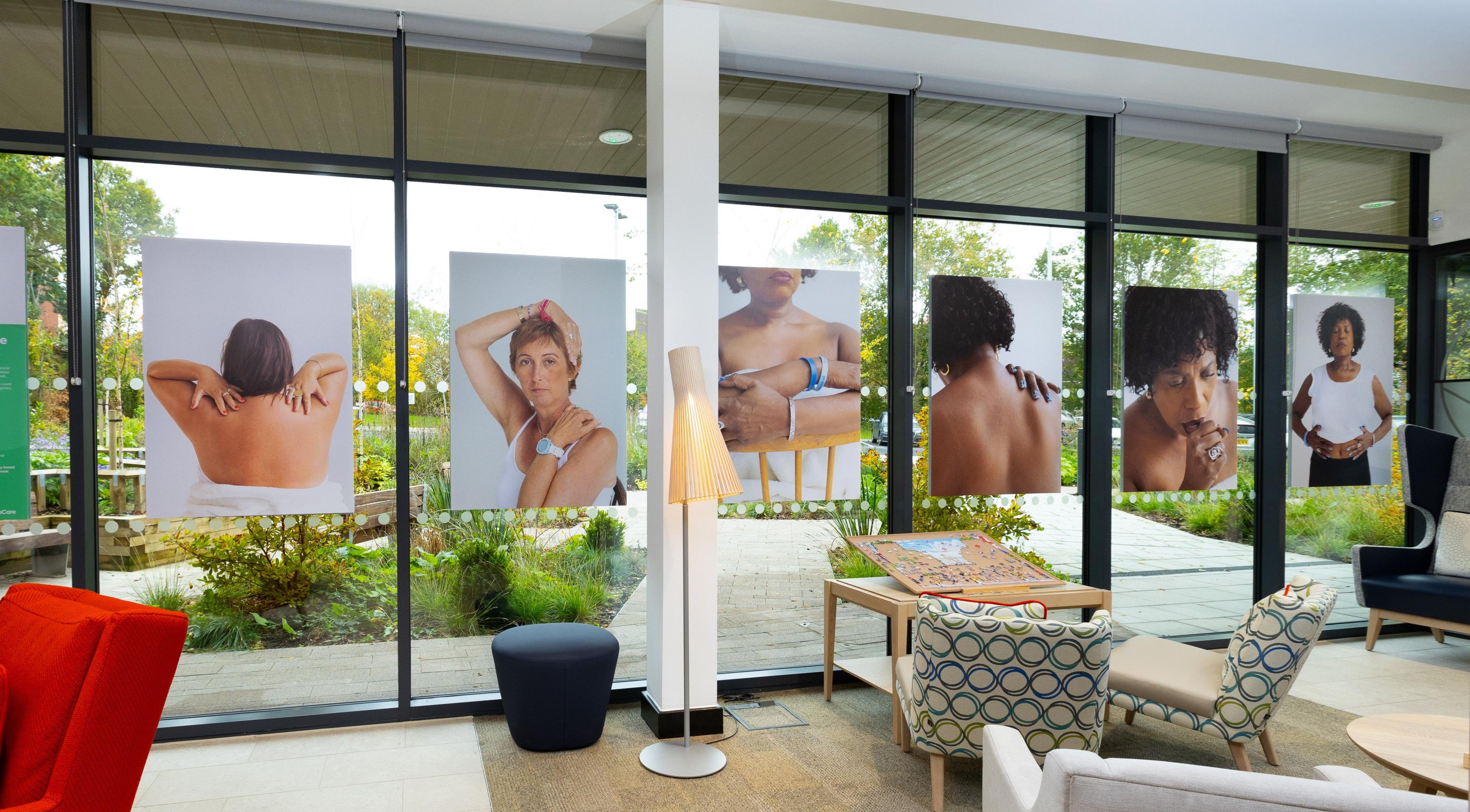 A row of six posters featuring secondary breast cancer patients are on the floor-to-ceiling windows of GenesisCare's facility