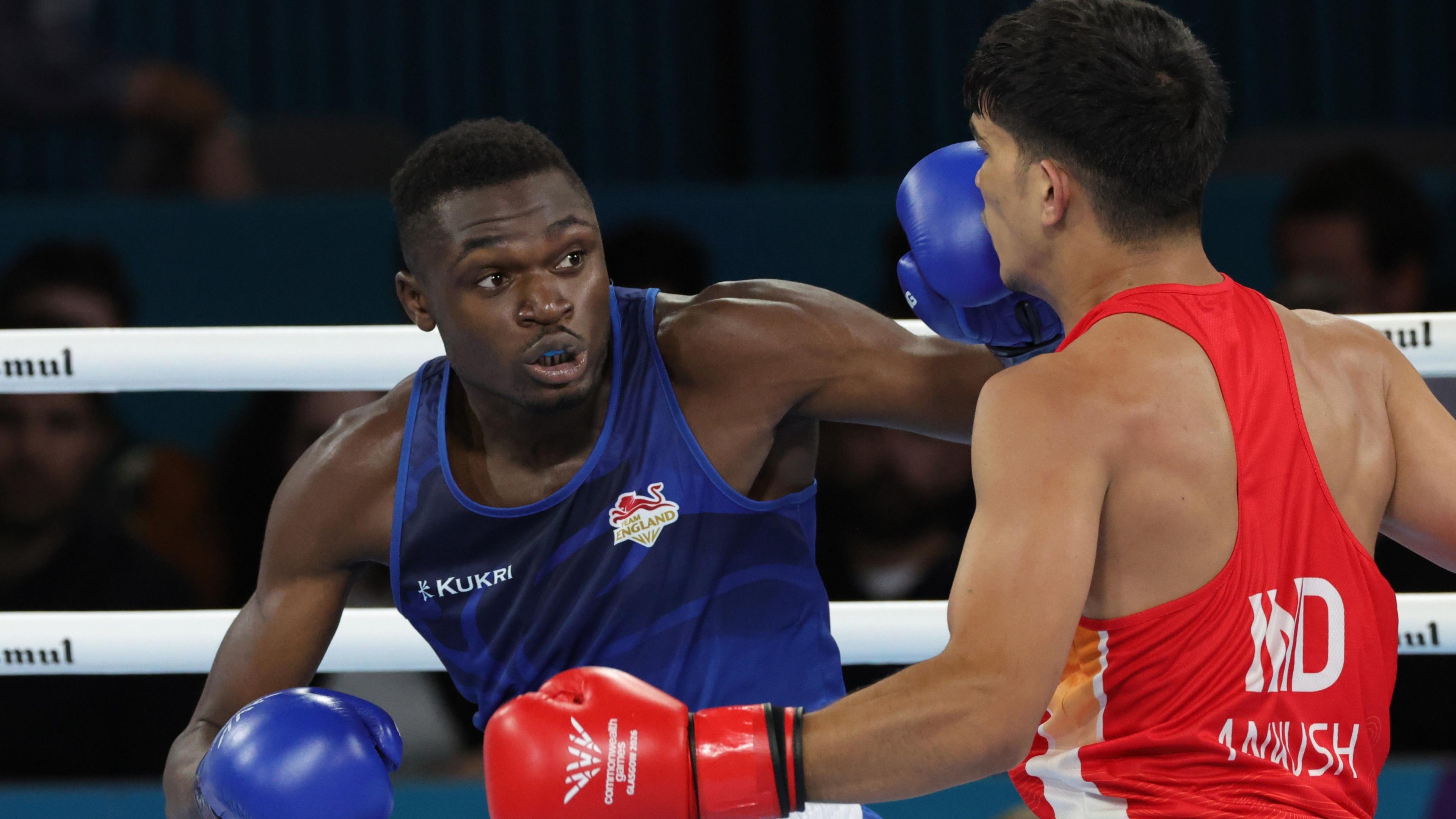 Dimeji Shittu, in blue, throws a punch in final. Opponent Ankush Panghal, in a red vest, is seen from behind