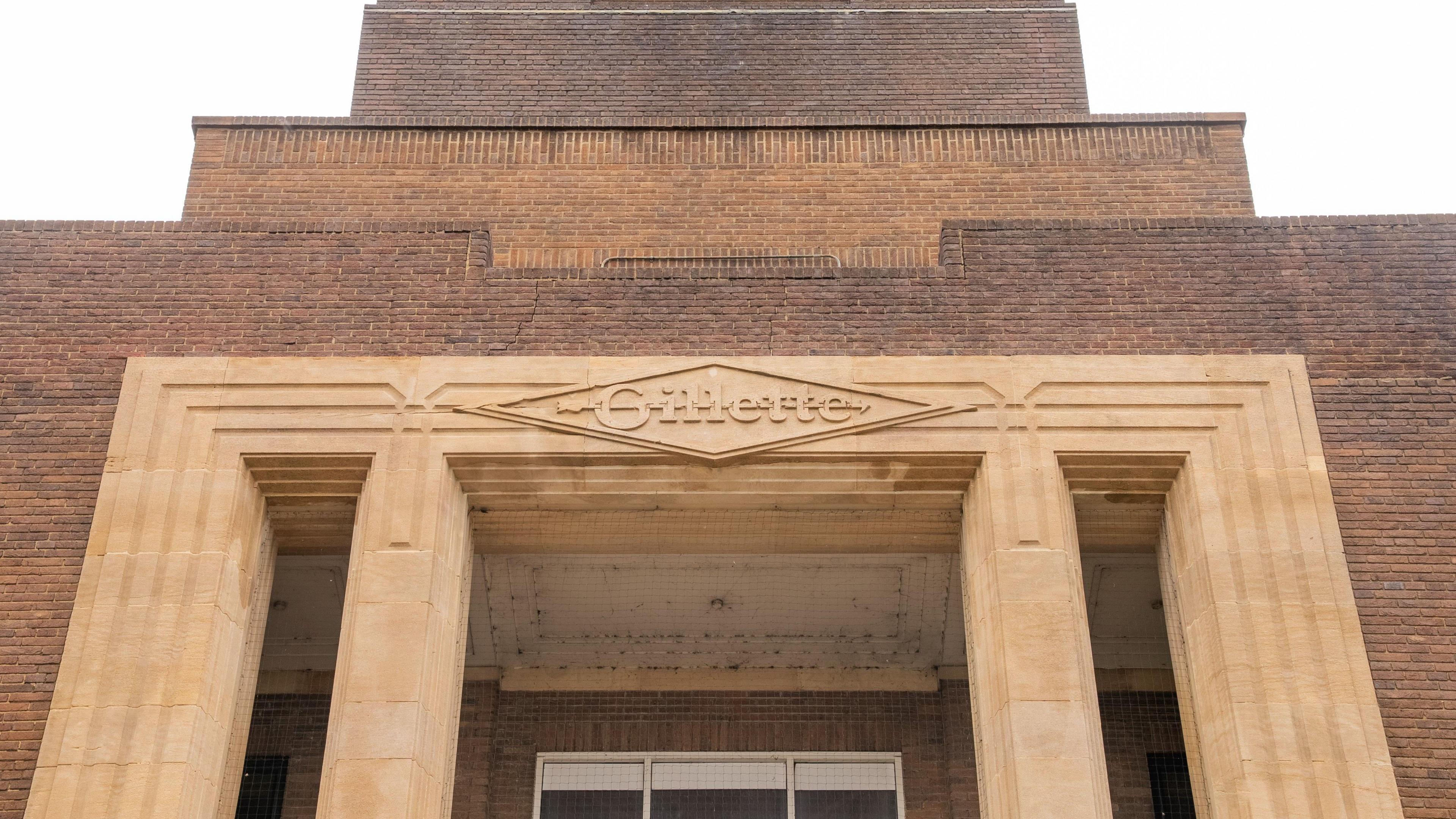 A close up of the detail of brown brick a 1930s Art Deco building with Gillette carved above the entrance.