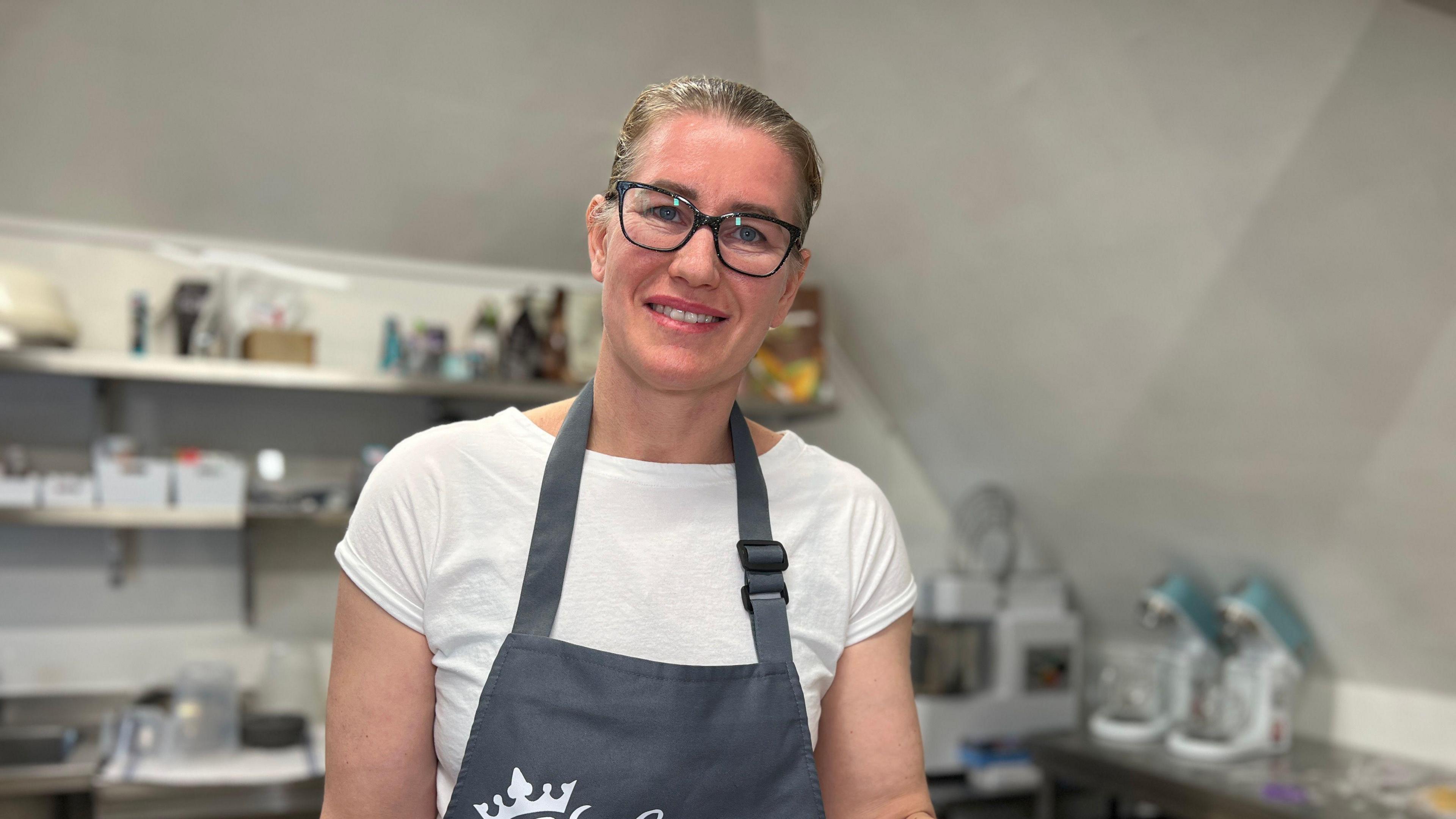 Nicoleta smiles at the camera in her bakery's kitchen wearing an apron 