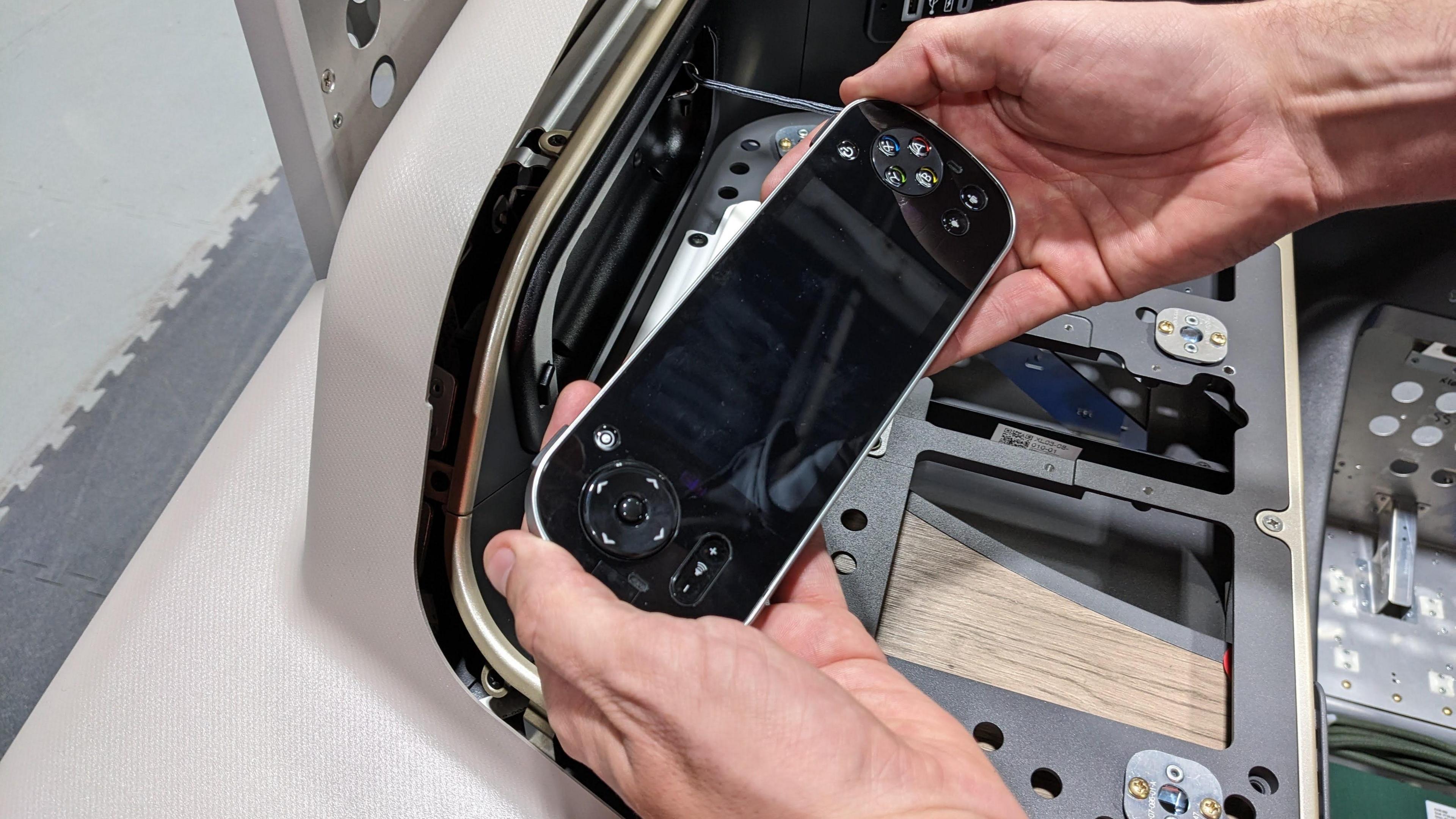 A man holds a media controller, which looks a bit like a handheld games console.