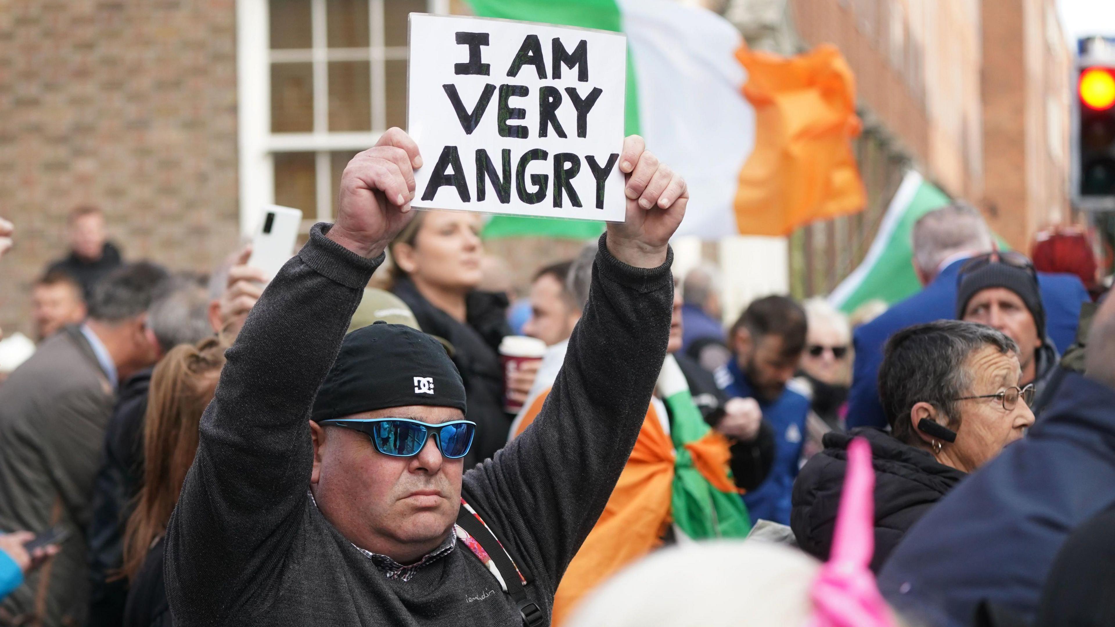 A man holds up a sign saying 'I am very angry'