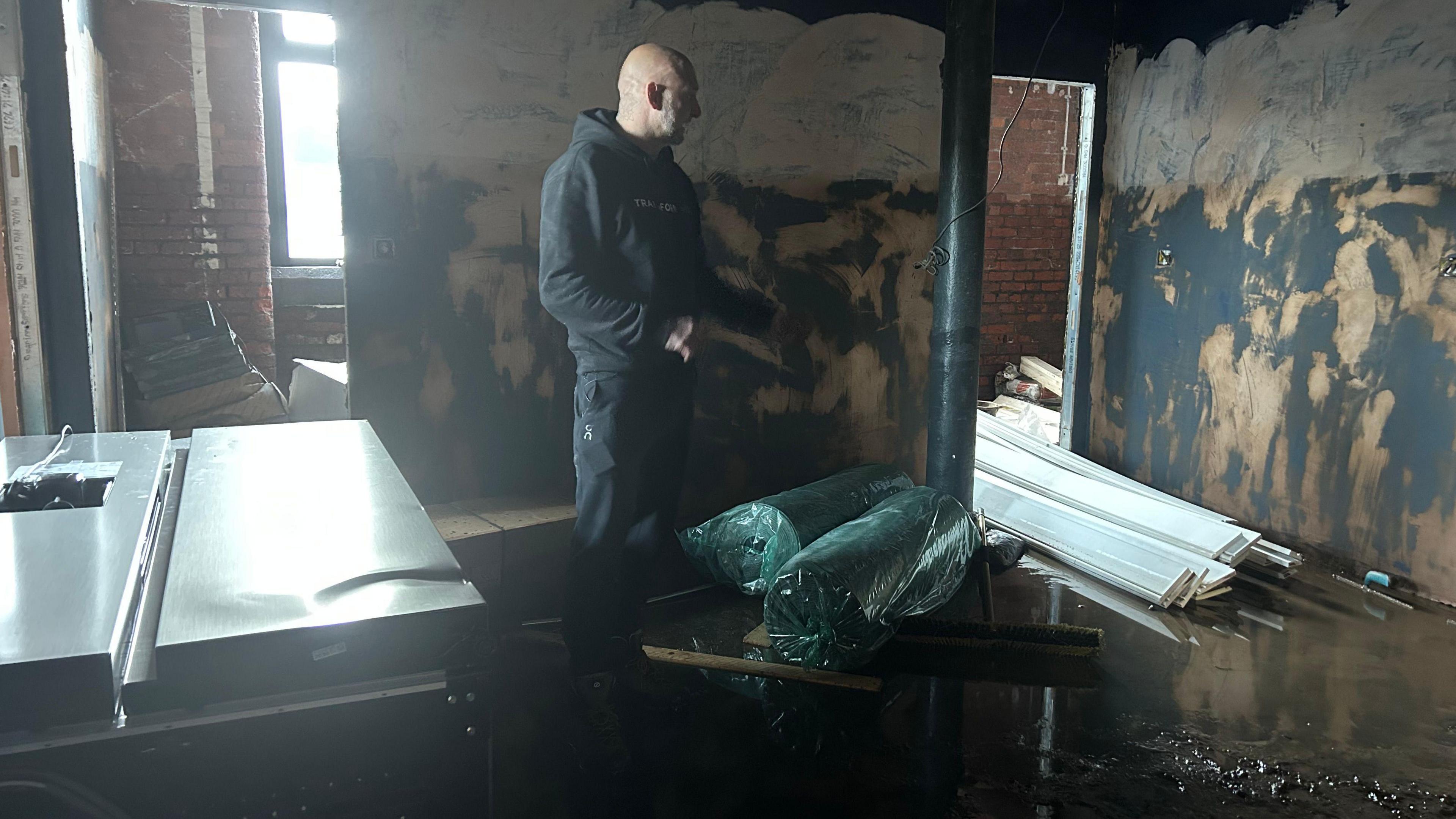 Man looks on as mud and water damages equipment in new gym building.