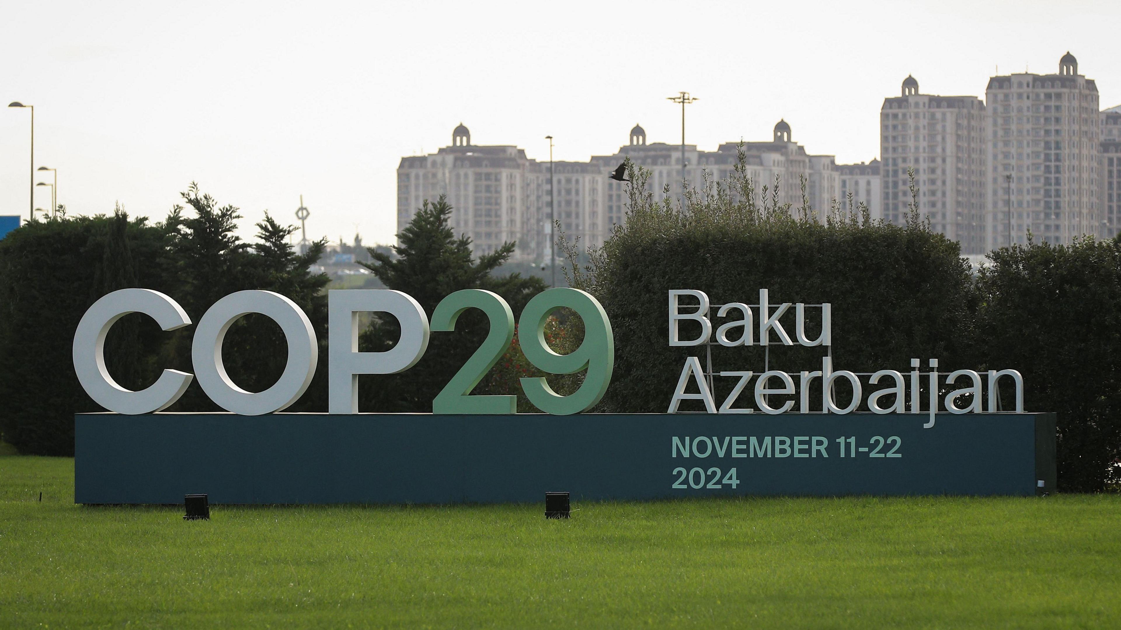 COP29 sign on a patch of grass with a backdrop of the cityscape in Baku, Azerbaijan