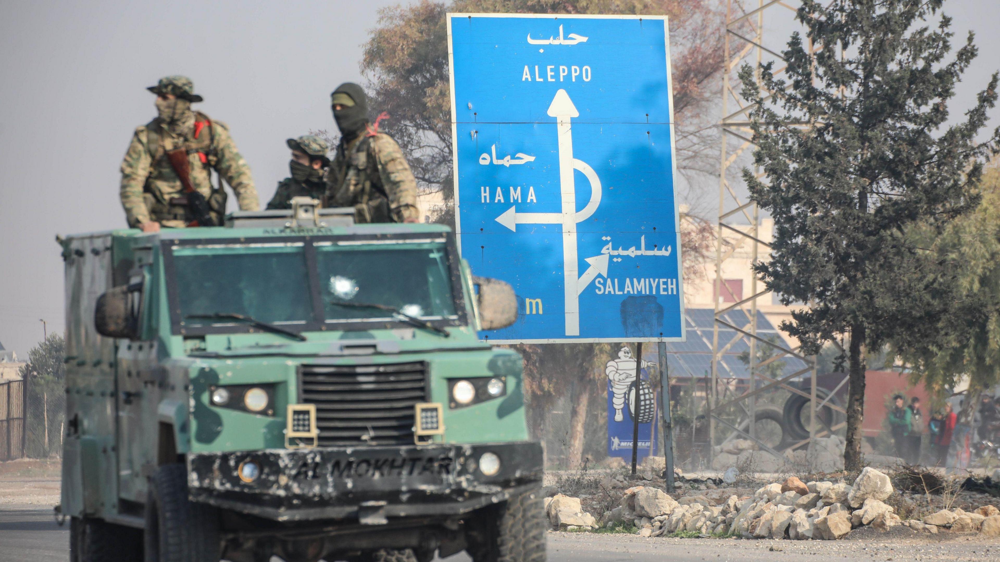 Anti-Assad fighters sit in an armoured van while advancing through Homs, the gateway to the capital Damascus