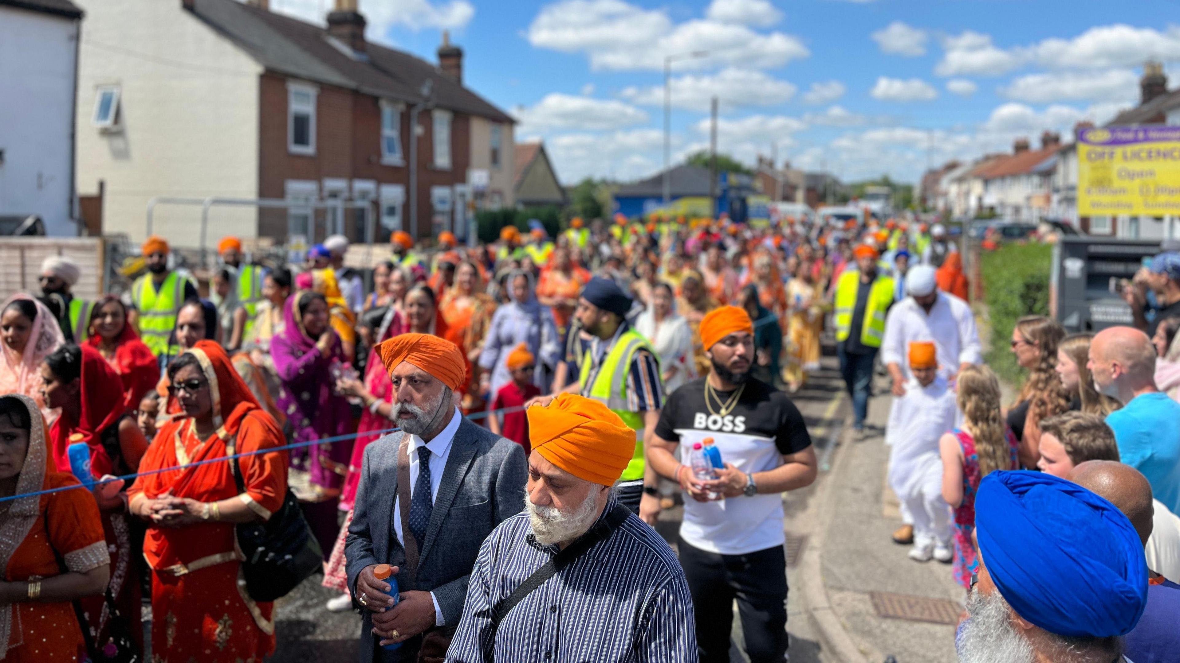 A large crowd of people following a decorated float on a residential street