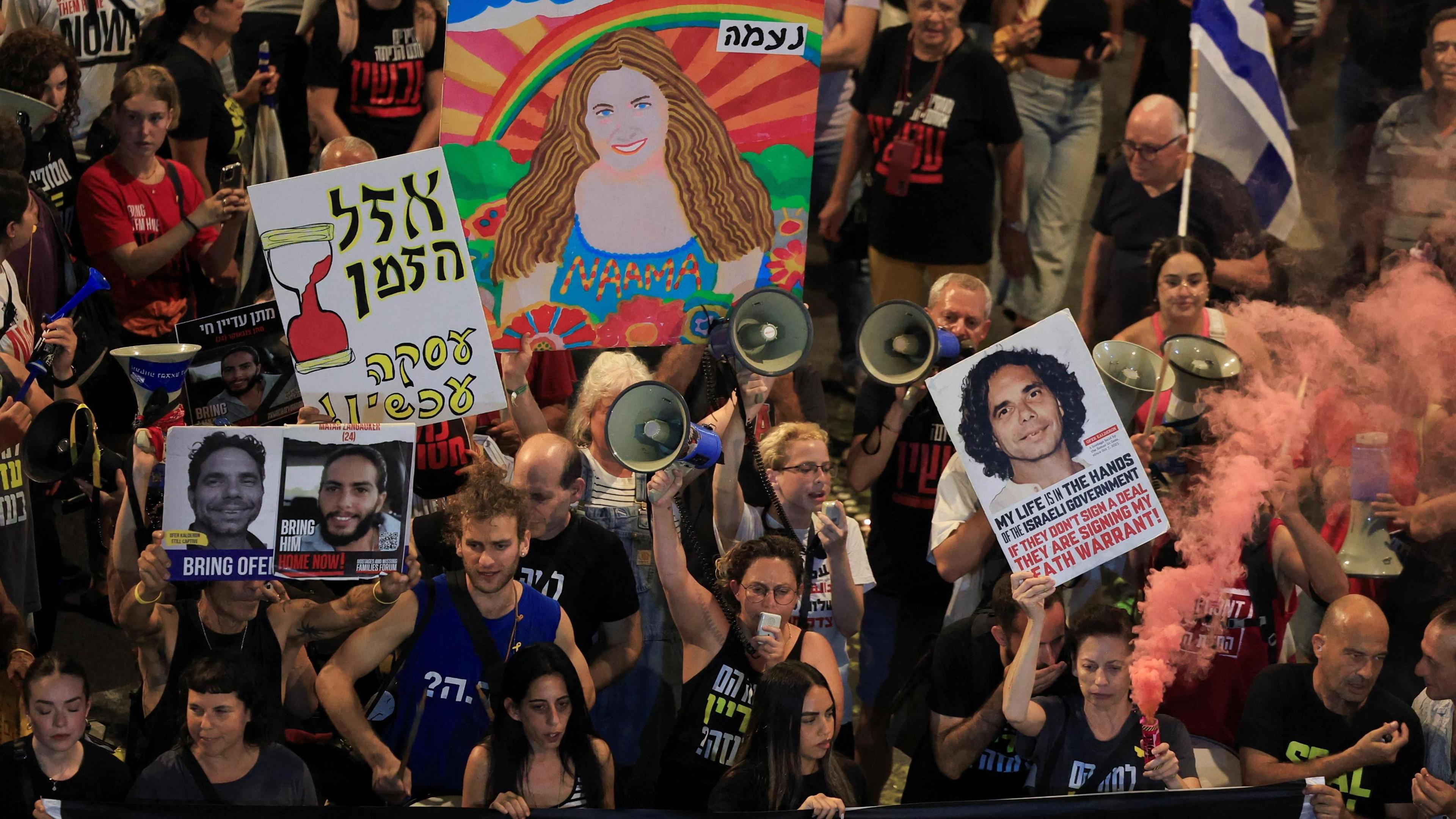 Demonstrators taking part in a protest to show support for the hostages who were kidnapped during the deadly October 7 attack wave banners bearing the faces of loved ones and set off flares.