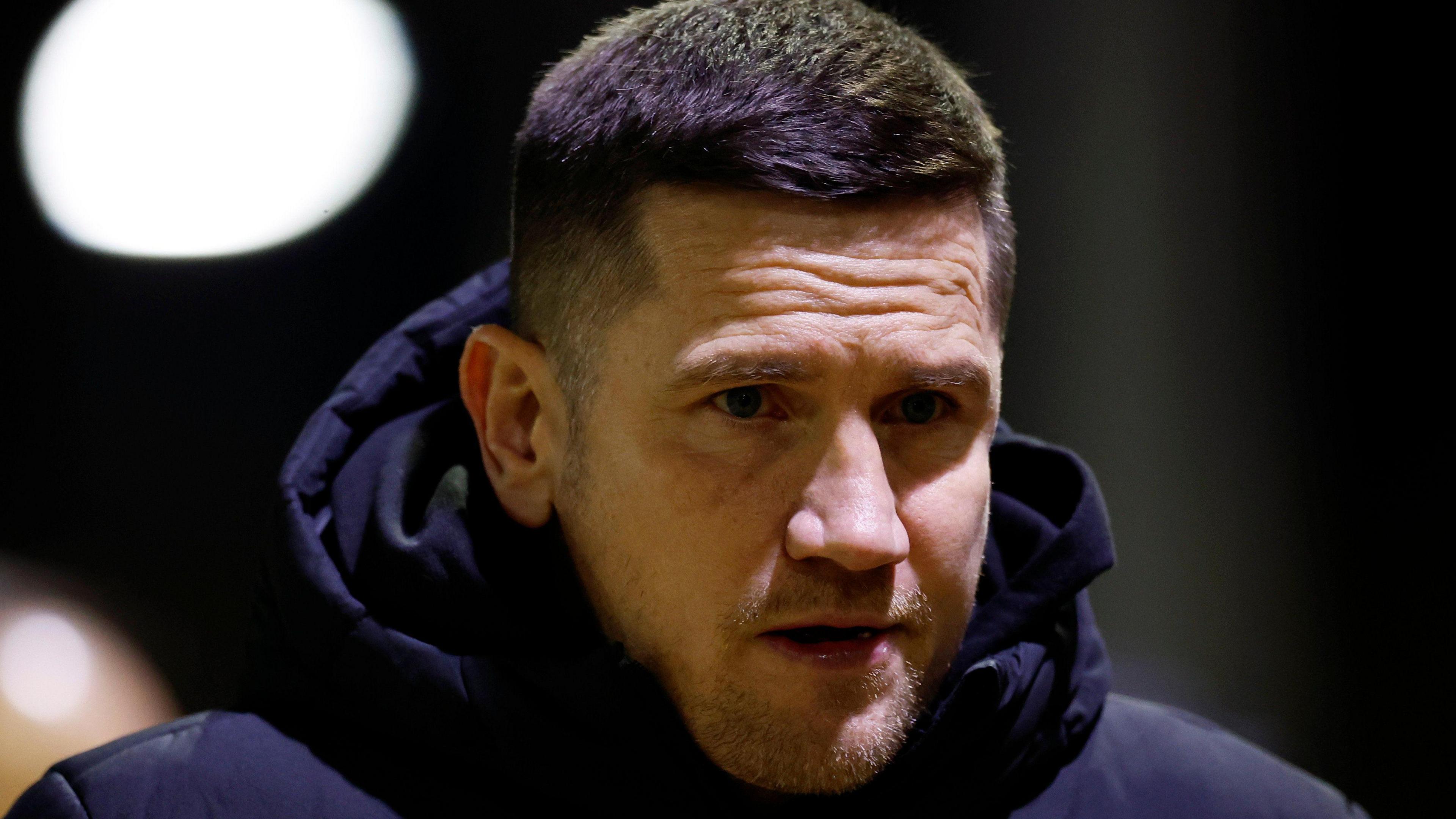 Lee Bell walks along the touchline in his Crewe puffer coat