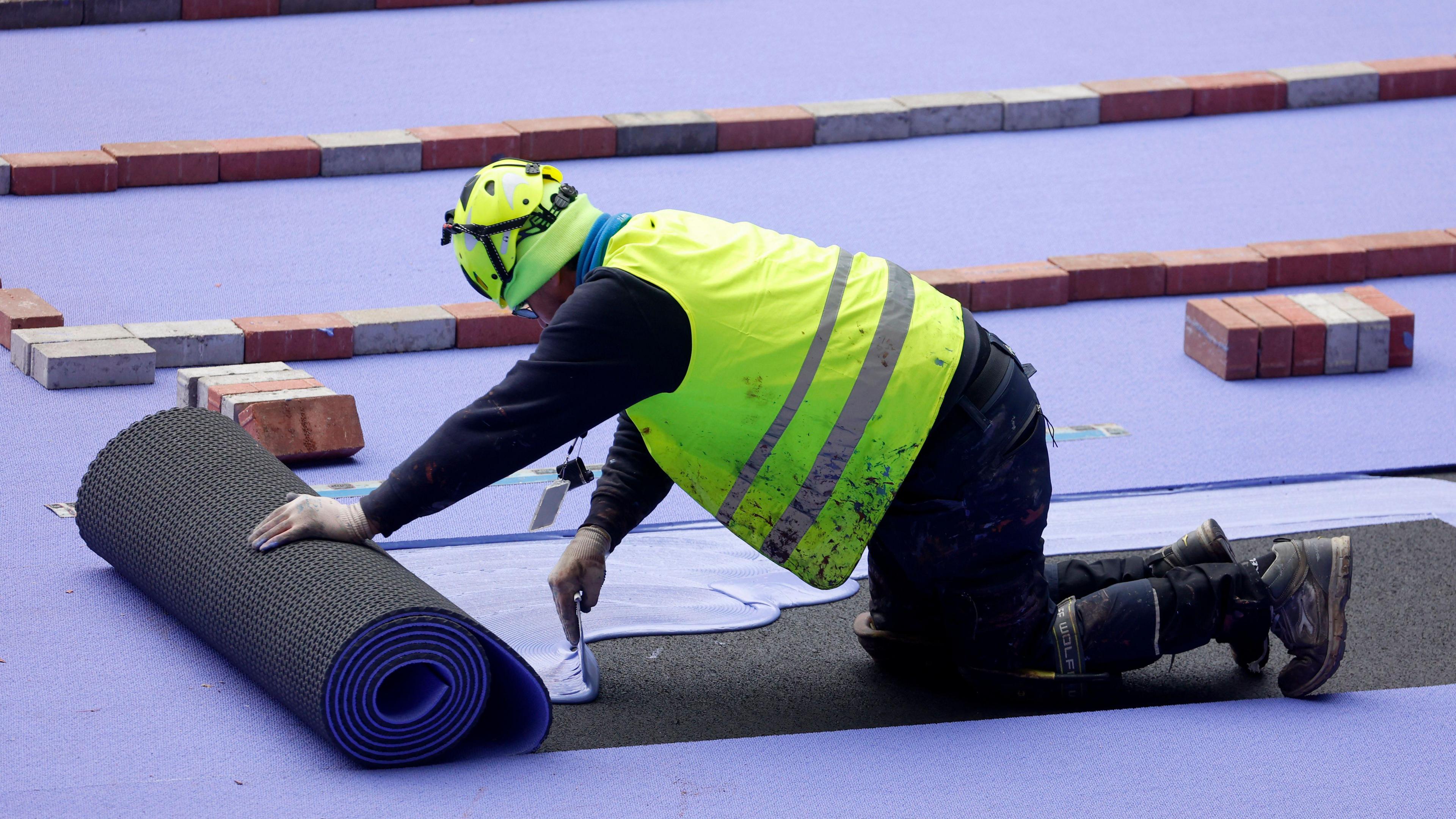 Worker lays the track at the Stade de France for the Paris Olympics