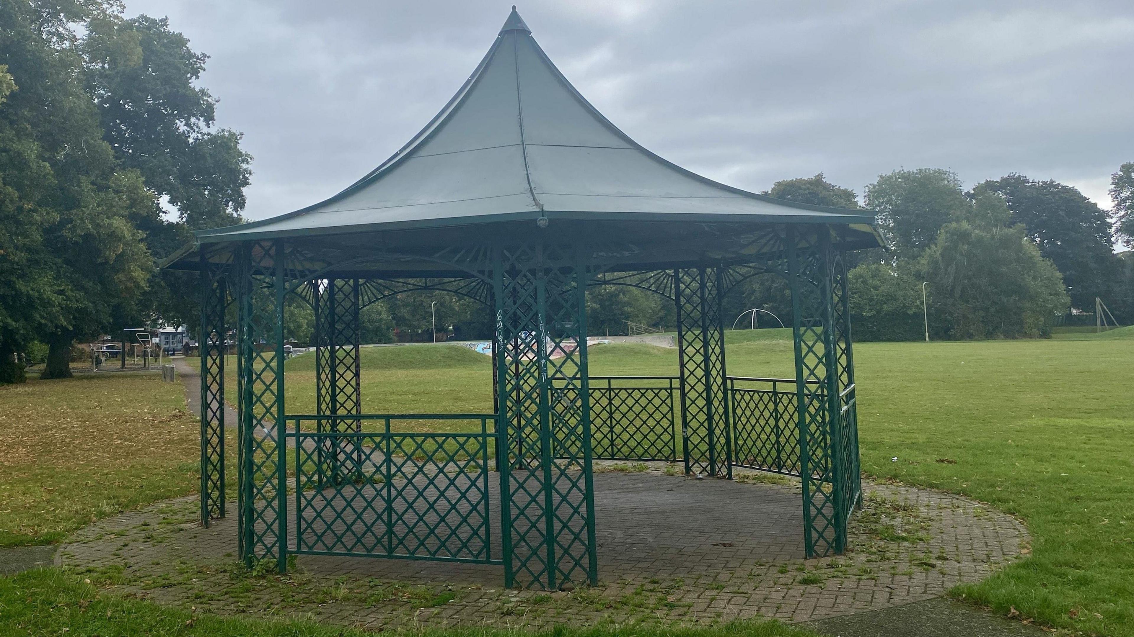 A lattice steel bandstand painted dark green