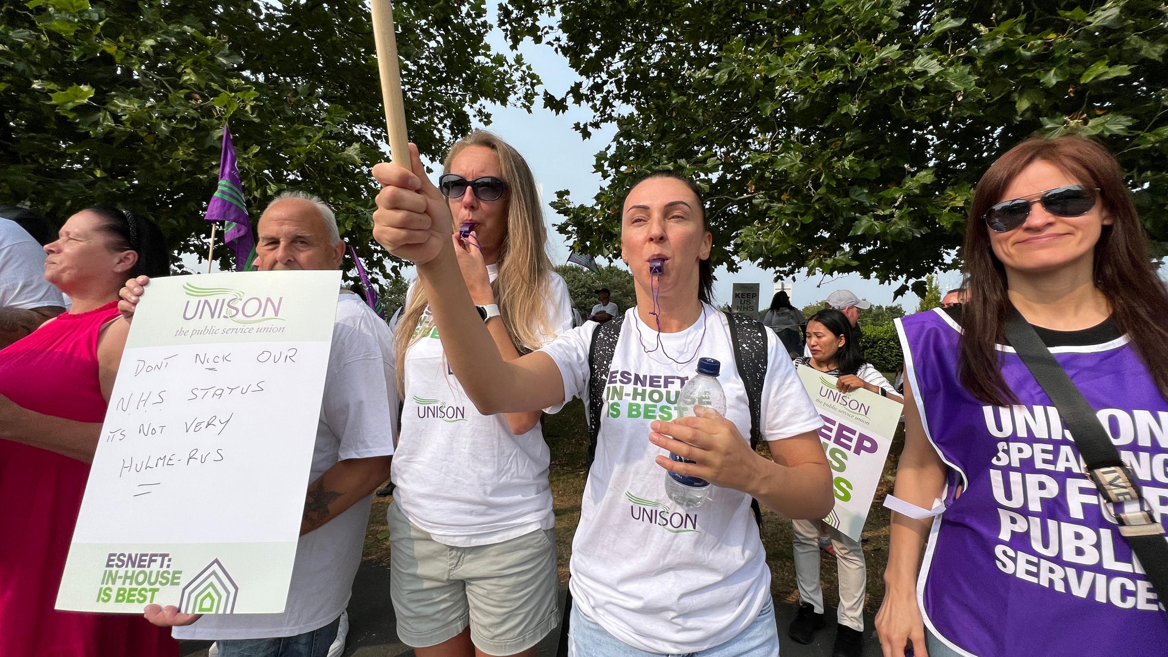 Members of non-medical staff on strike outside Colchester Hospital with placards and whistles