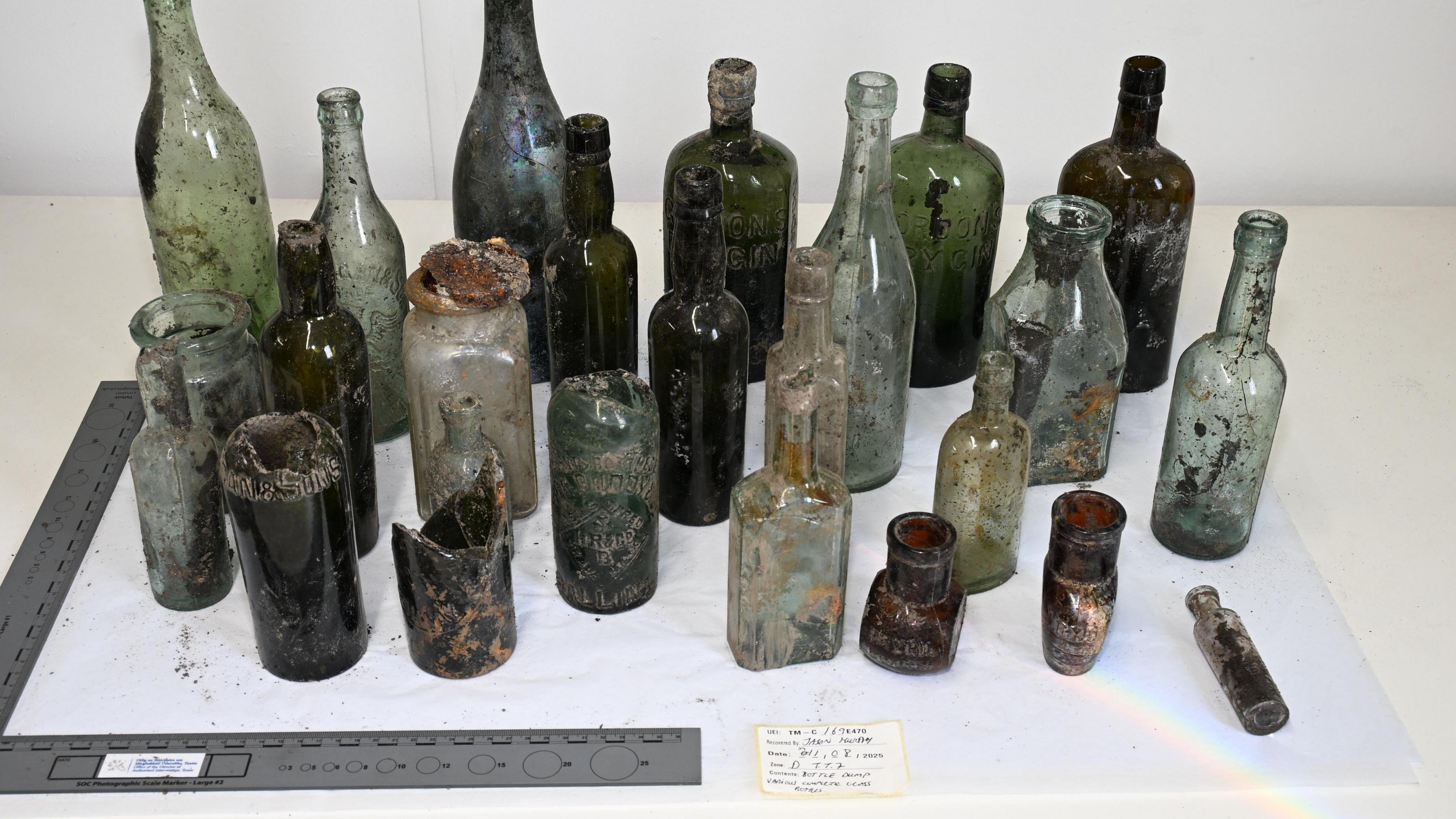A number of glass bottles of various sizes and colours on a white background.