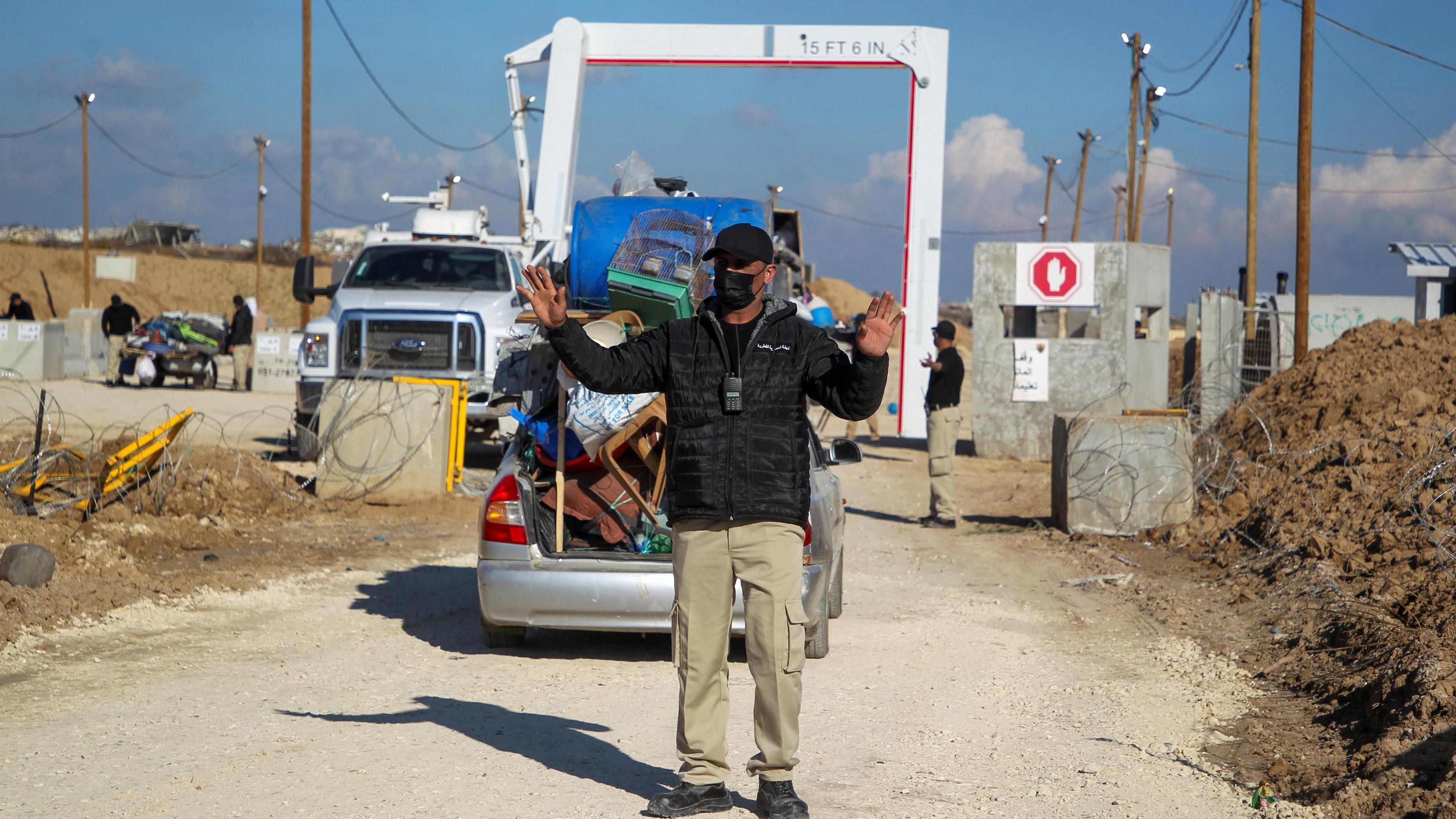 A member of the Egyptian-Qatari committee gestures while inspecting vehicles carrying displaced Palestinians at a screening area south of Gaza City (27 January 2025)