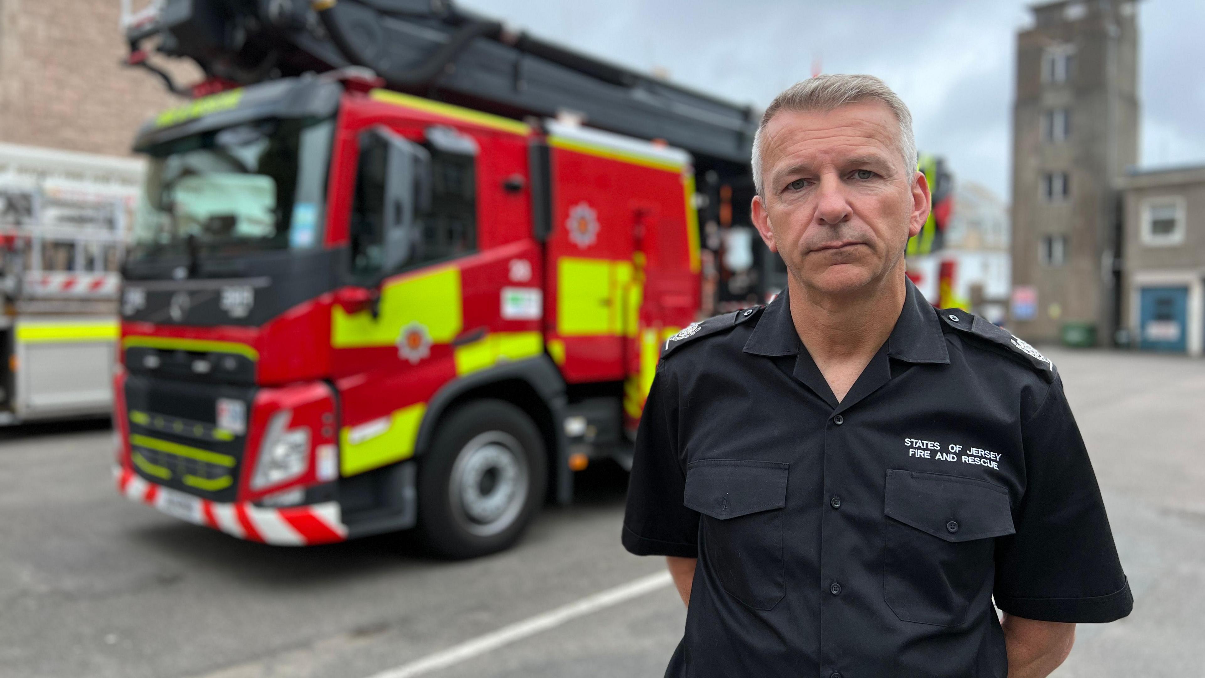 States of Jersey Fire and Rescue Service Area Commander, Jason Masterman, stands in front of a fire engine.