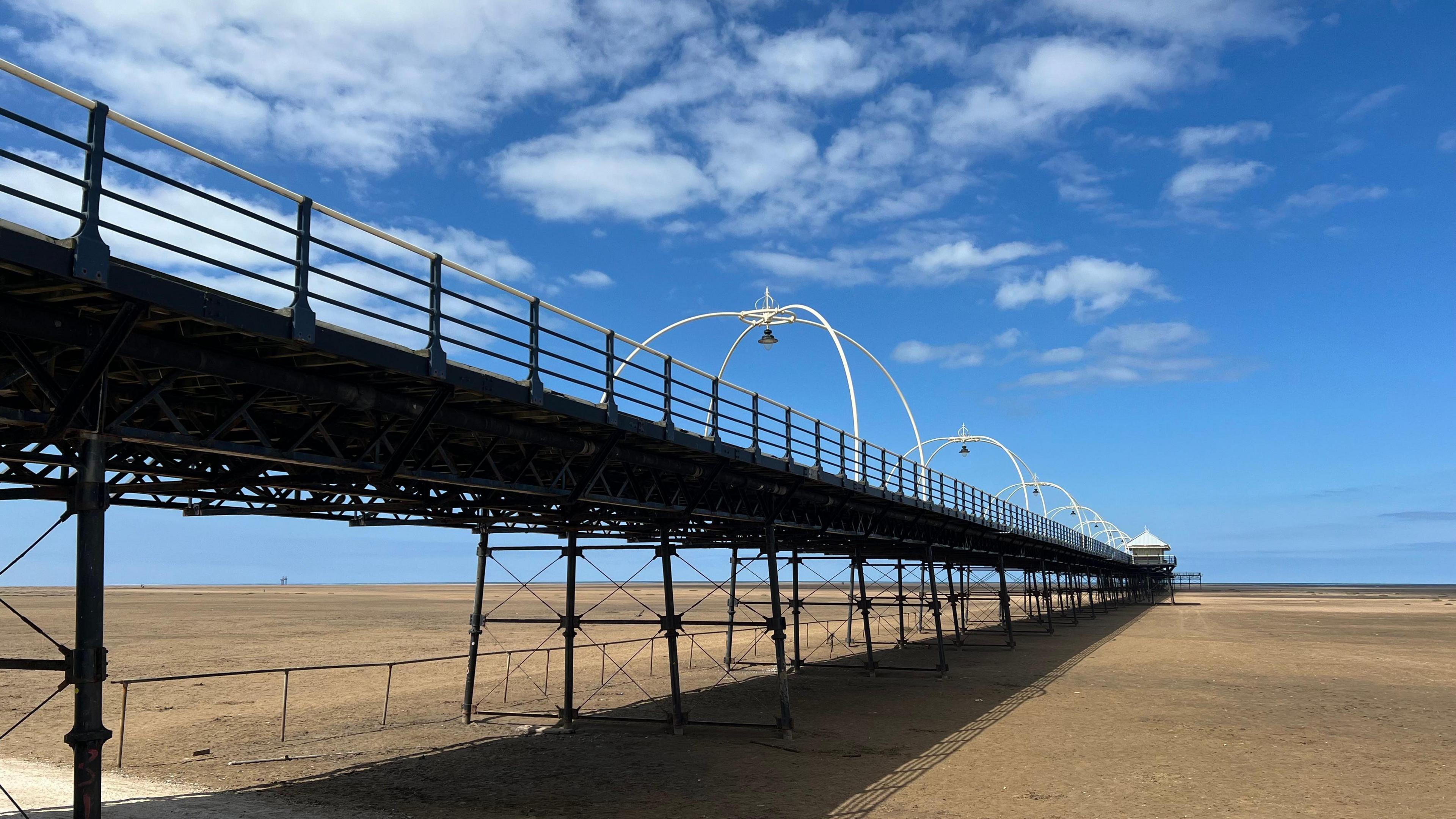Southport pier taken from below on the beach - golden sand stretches out to the sea which is far away