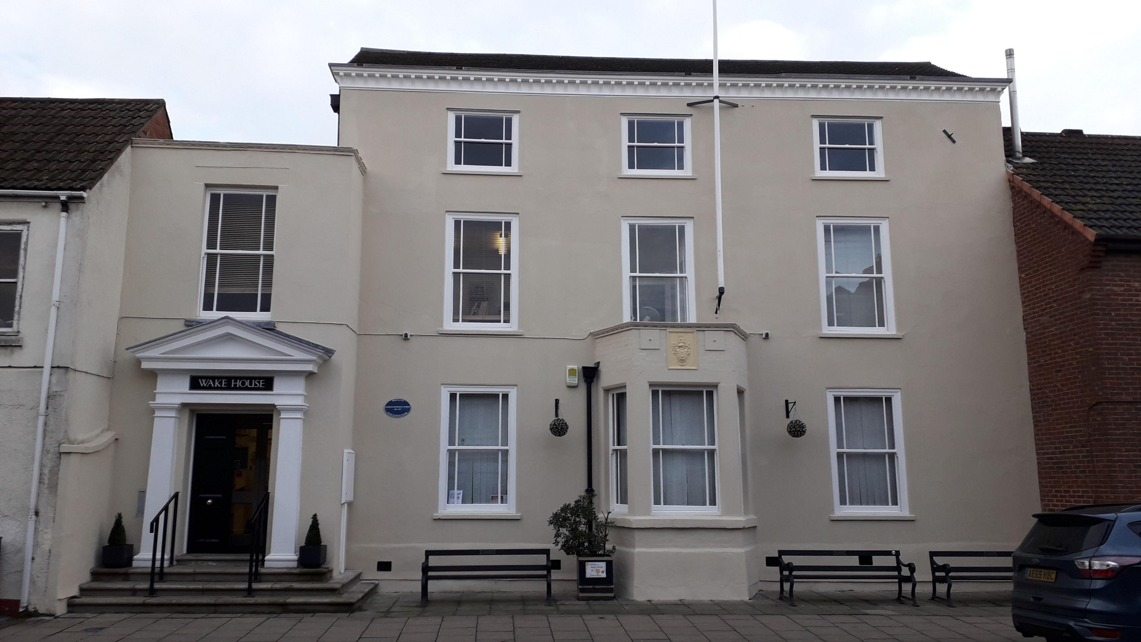 A photograph of Wake House, taken from outside. It is a two storey building with a bay window and a black front door.