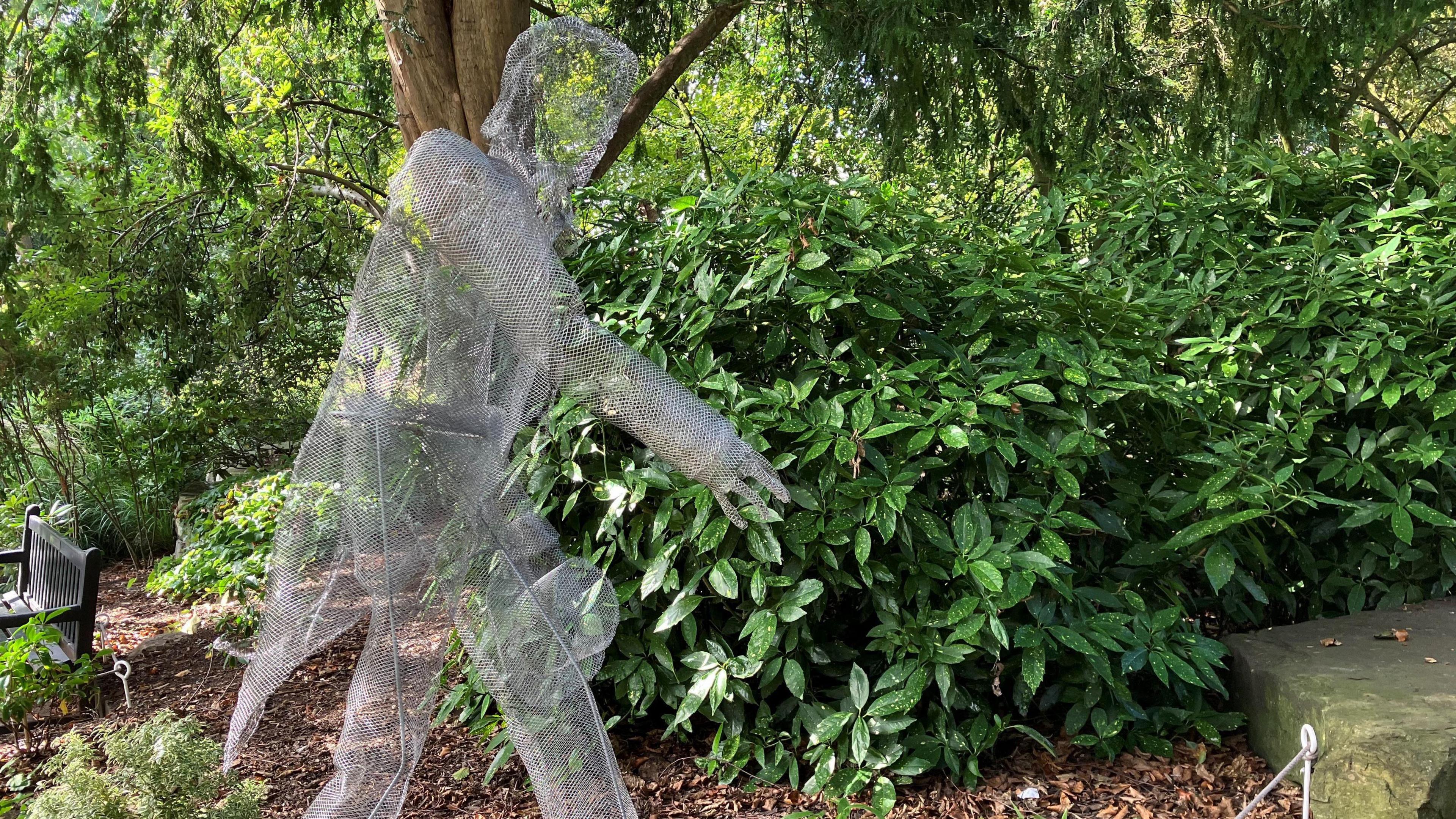 A wire sculpture of a historical man stands in a public garden in York.