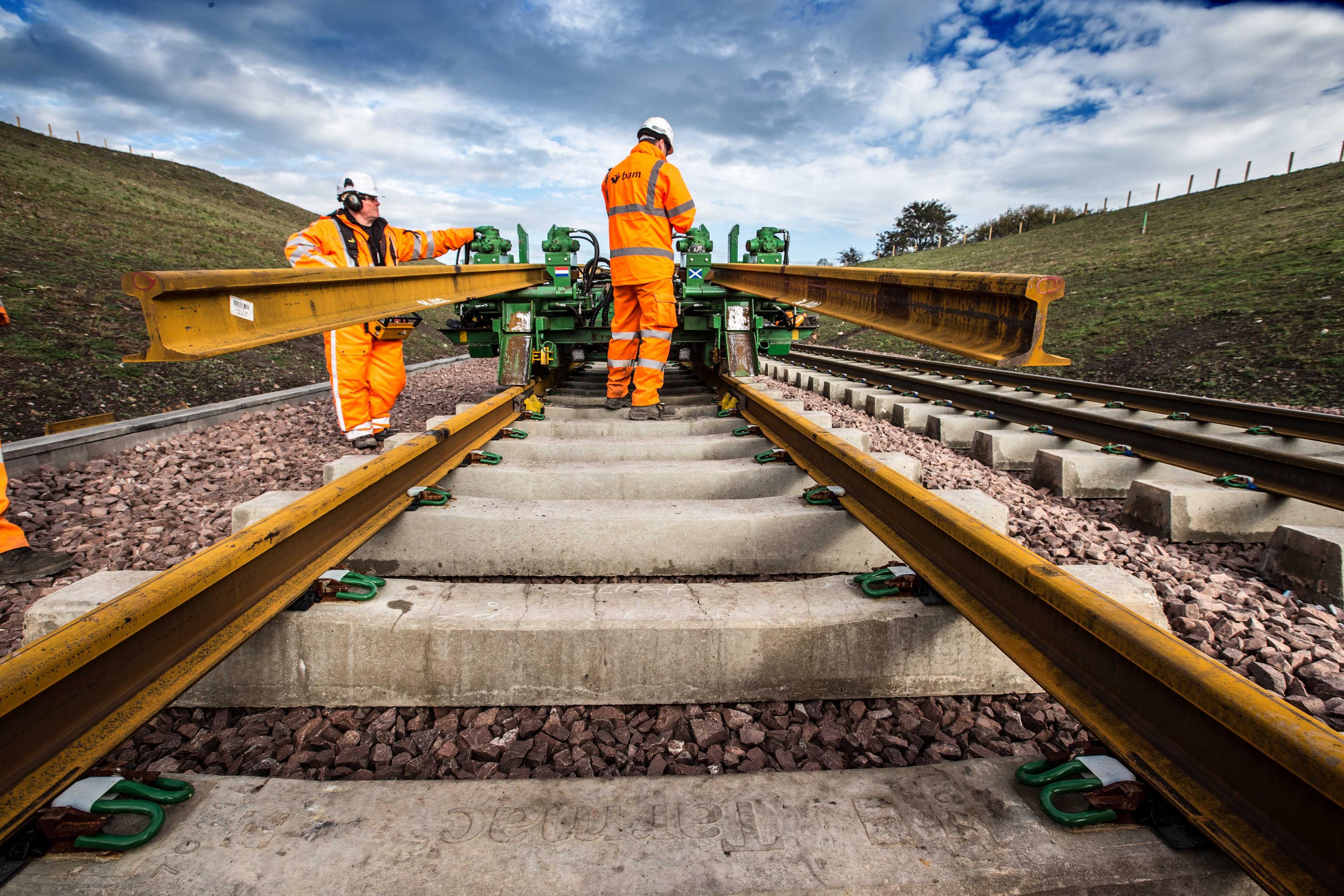 Workers on the Borders Railway line in bright orange clothing and hard hats are laying the track for the route