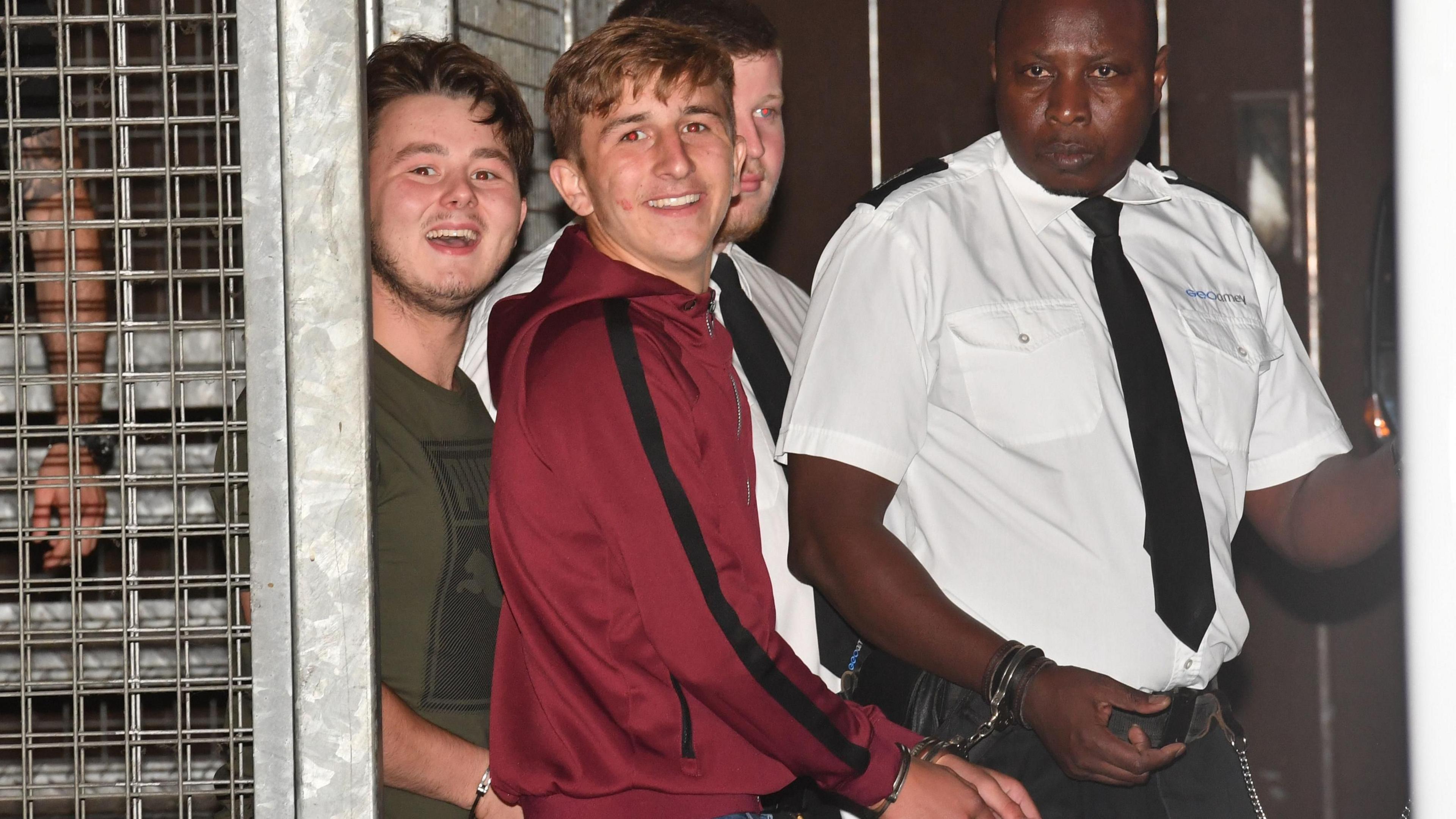 Albert Bowers and Jessie Cole smile as they are led in handcuffs by two prison officers