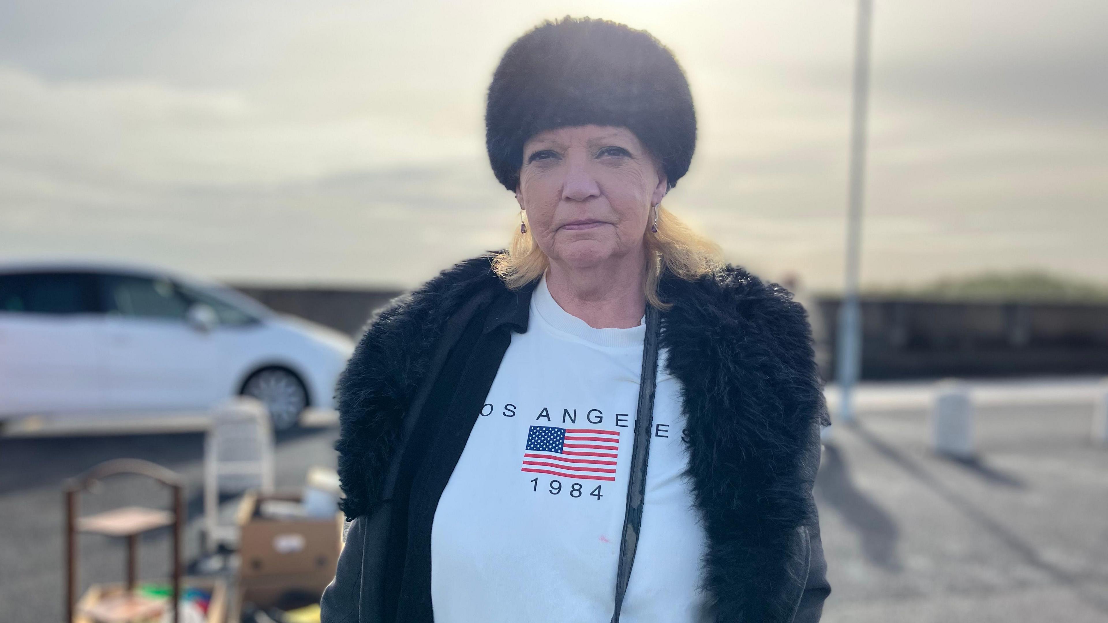 A woman with a woolly hat and coat with a white t-shirt underneath