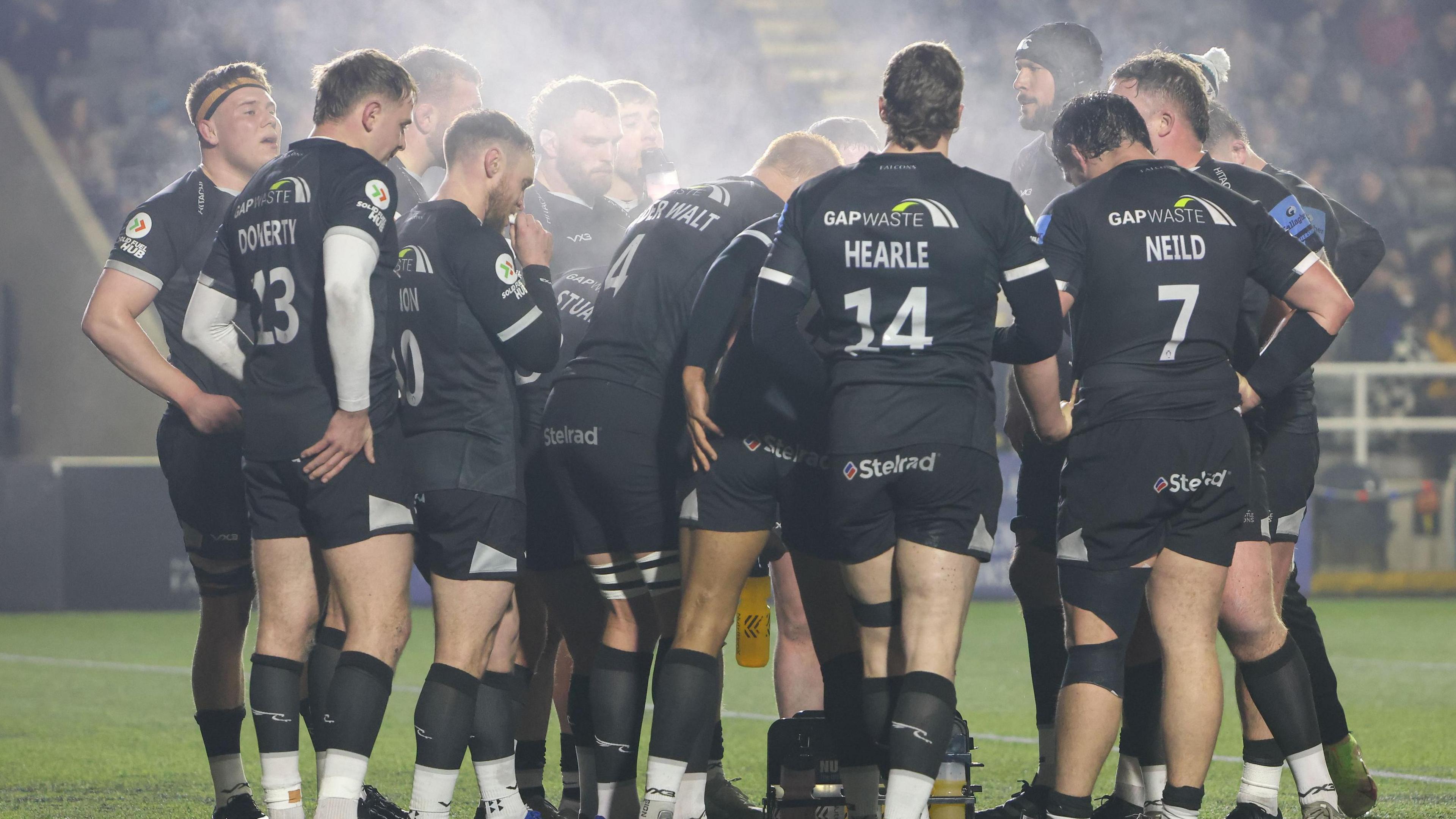 Newcastle players stand in a huddle on the pitch