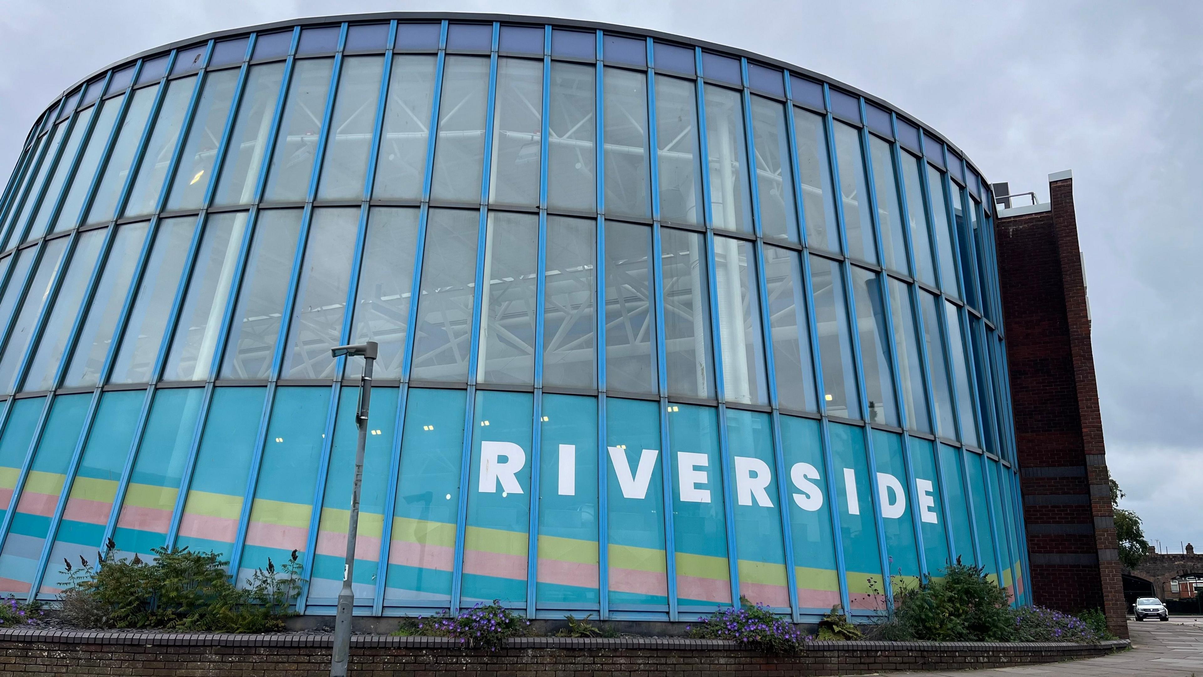 The exterior of the Riverside Leisure Centre in Exeter, which features a mix of glass, blue metal cladding, concrete and large windows to provide natural light into the pool and gym areas.