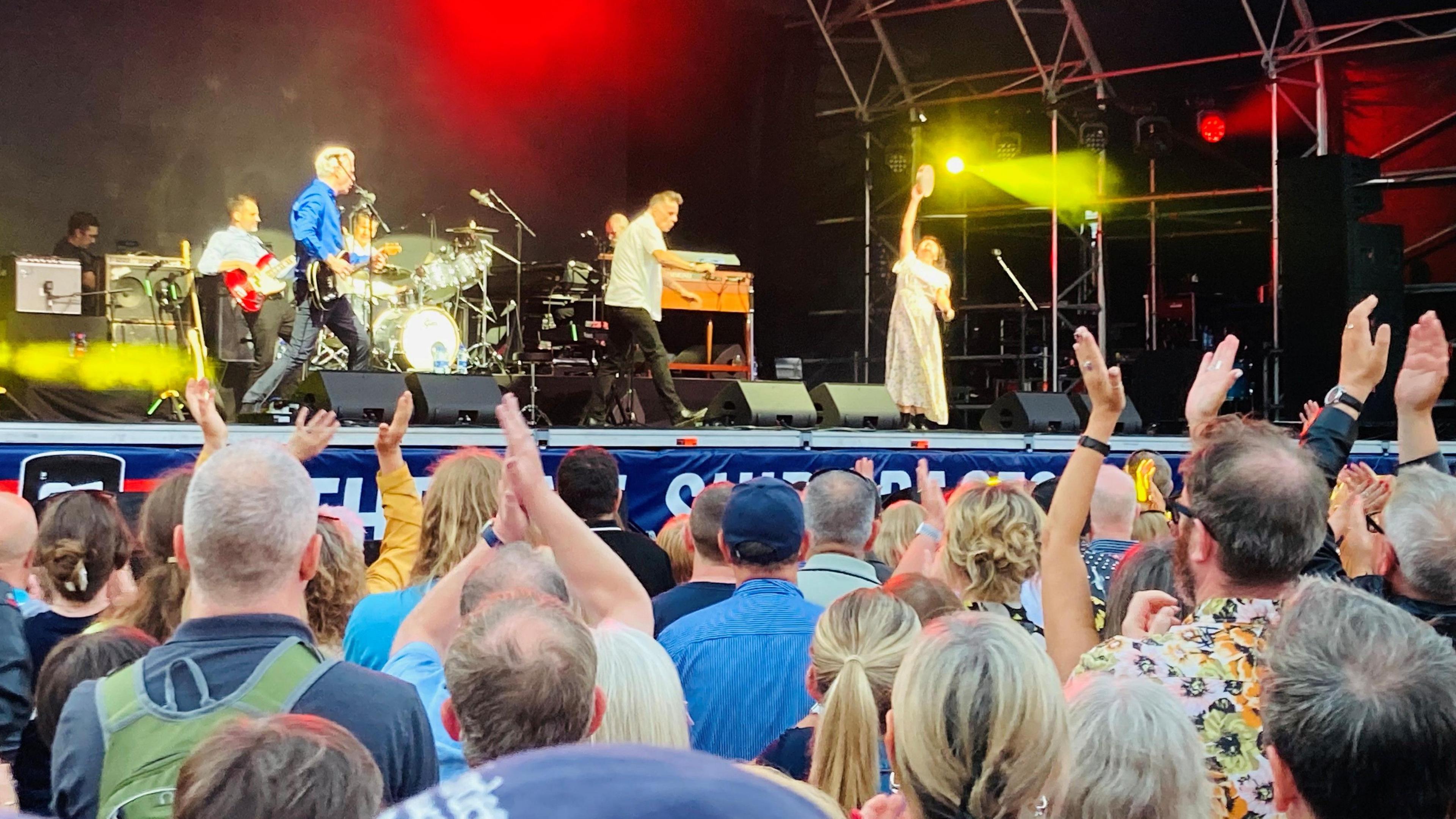 Deacon Blue on stage in Aberdeen. They are dancing about. The crowd looks happy.
