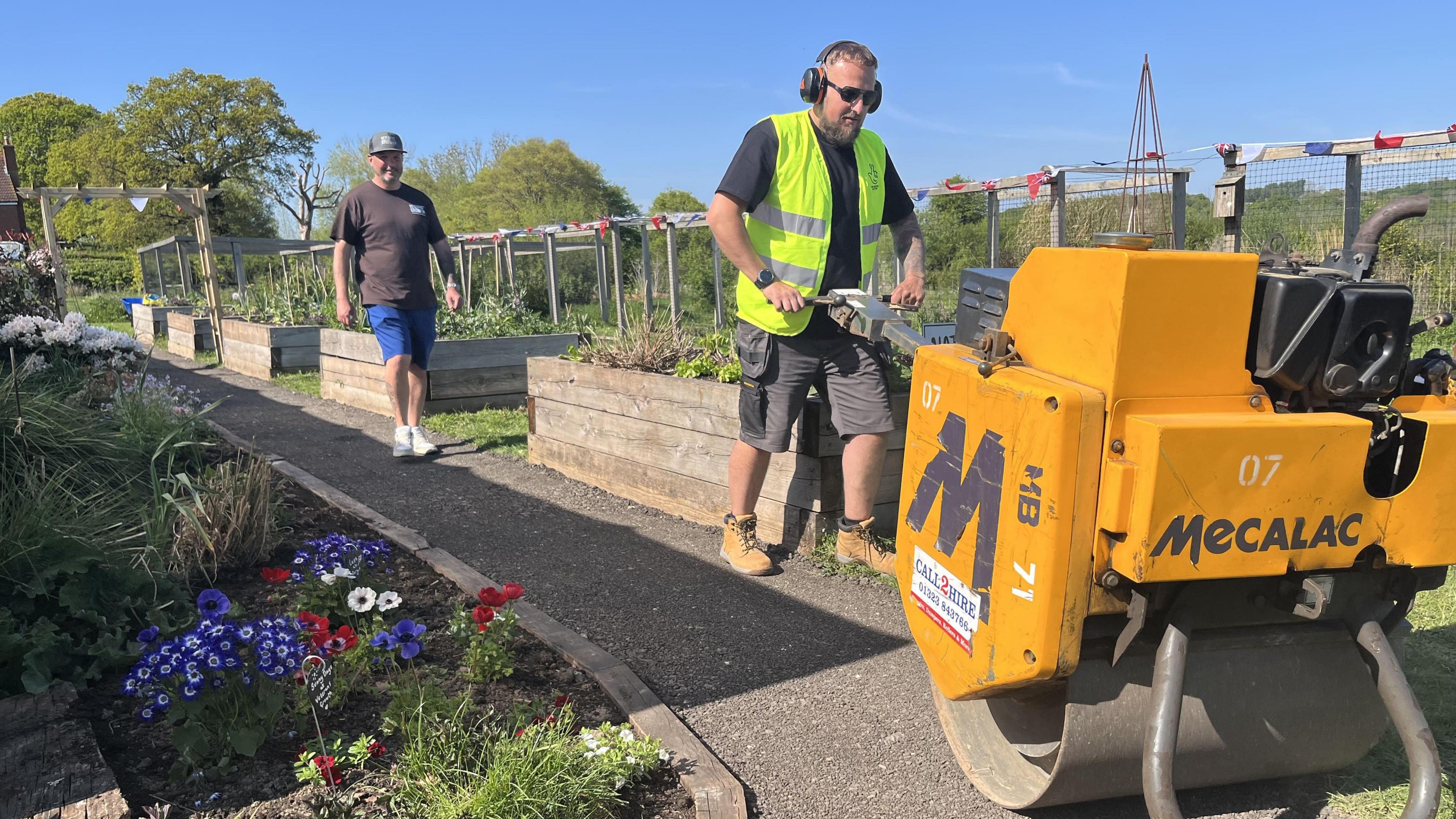 A man pushes a cement mixer along the new path at charity Veterans Growth 
