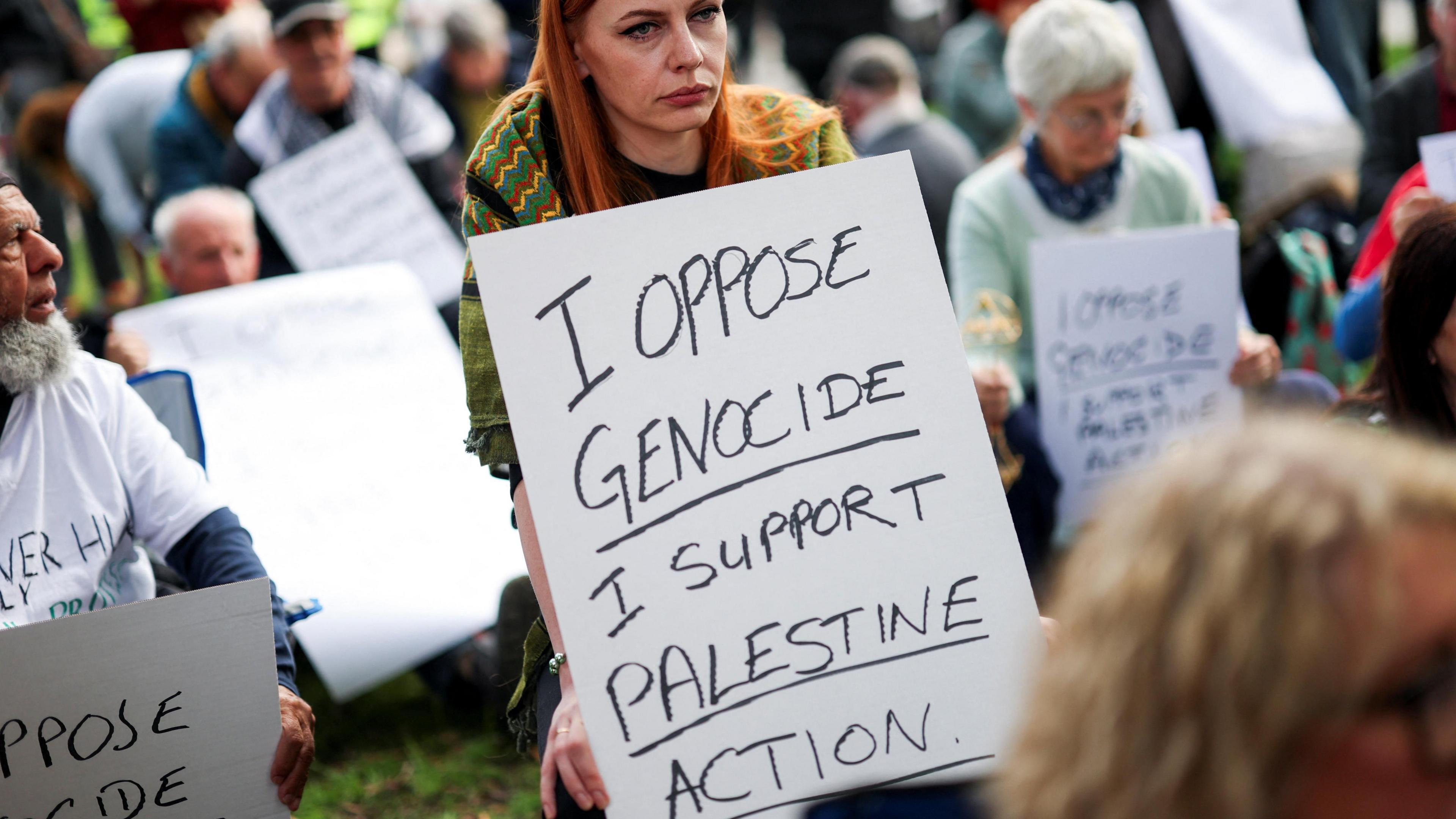 A woman with long red hair  holds a placard during a 'Lift the Ban on Palestine Action' can