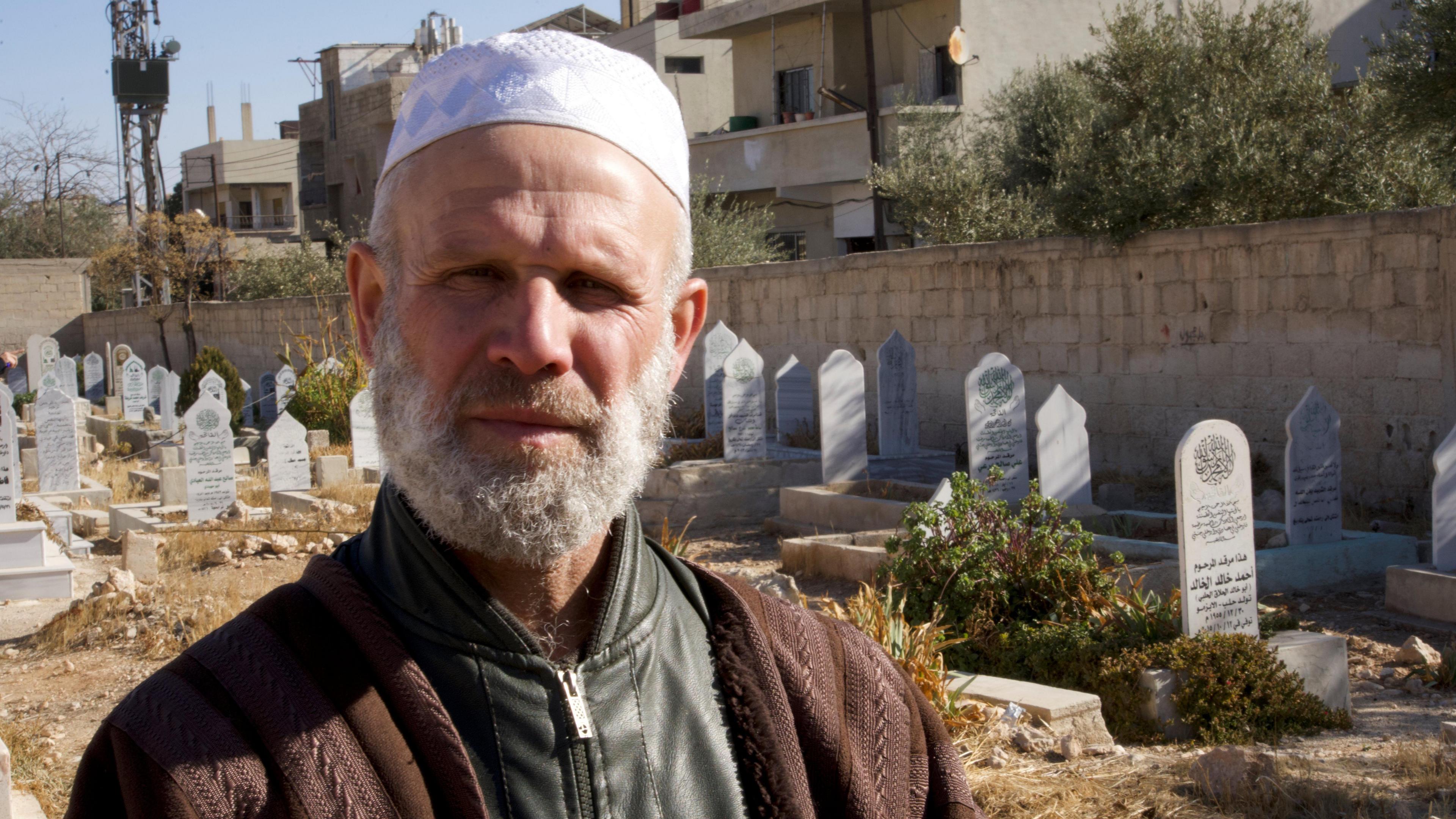 Abdul Kader al-Sheikha, a Muslim cleric, stands in Qutayfah cemetery