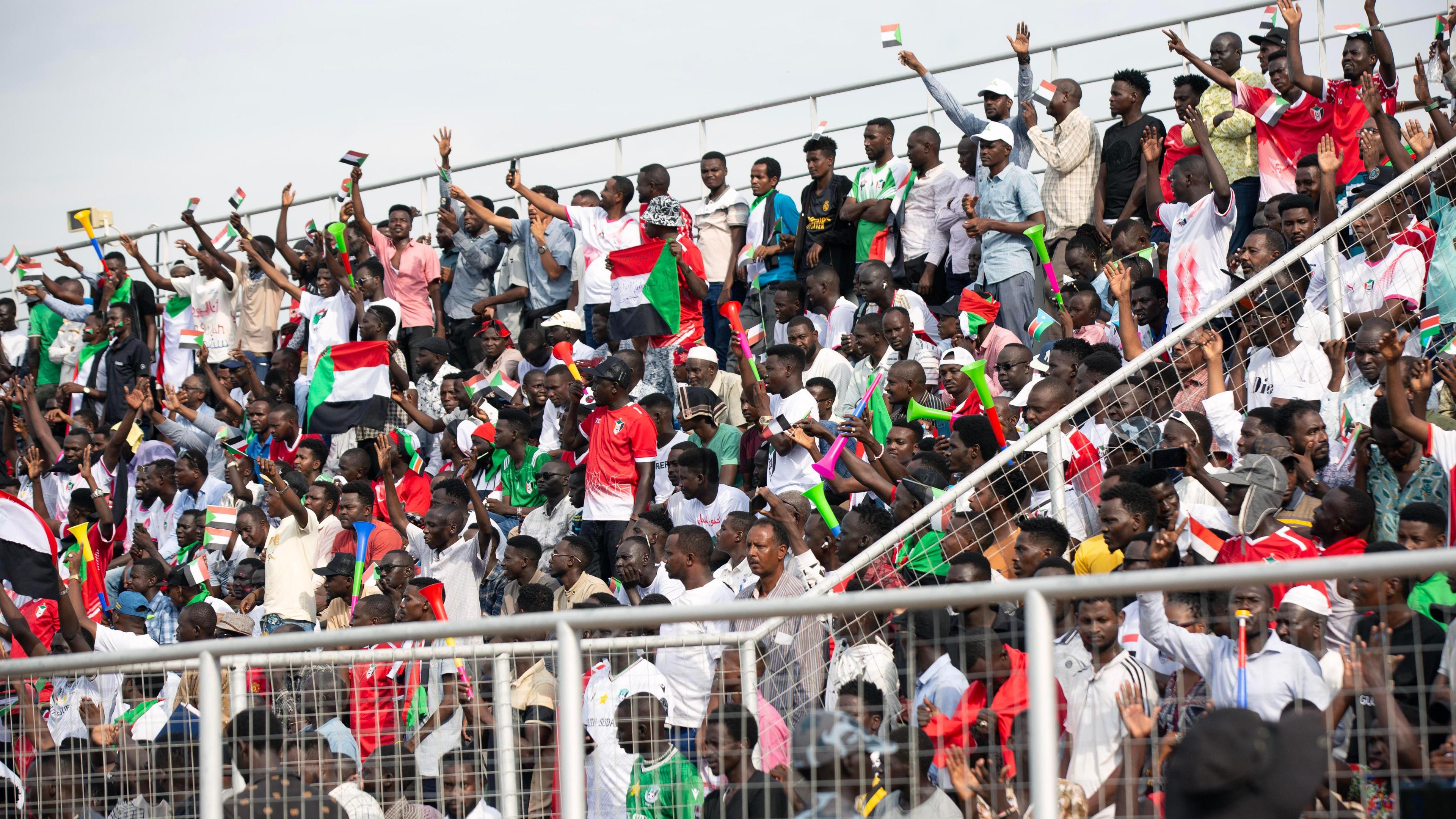 Sudan fans shout and wave flags in the stands during a World Cup qualifier against South Sudan in Juba