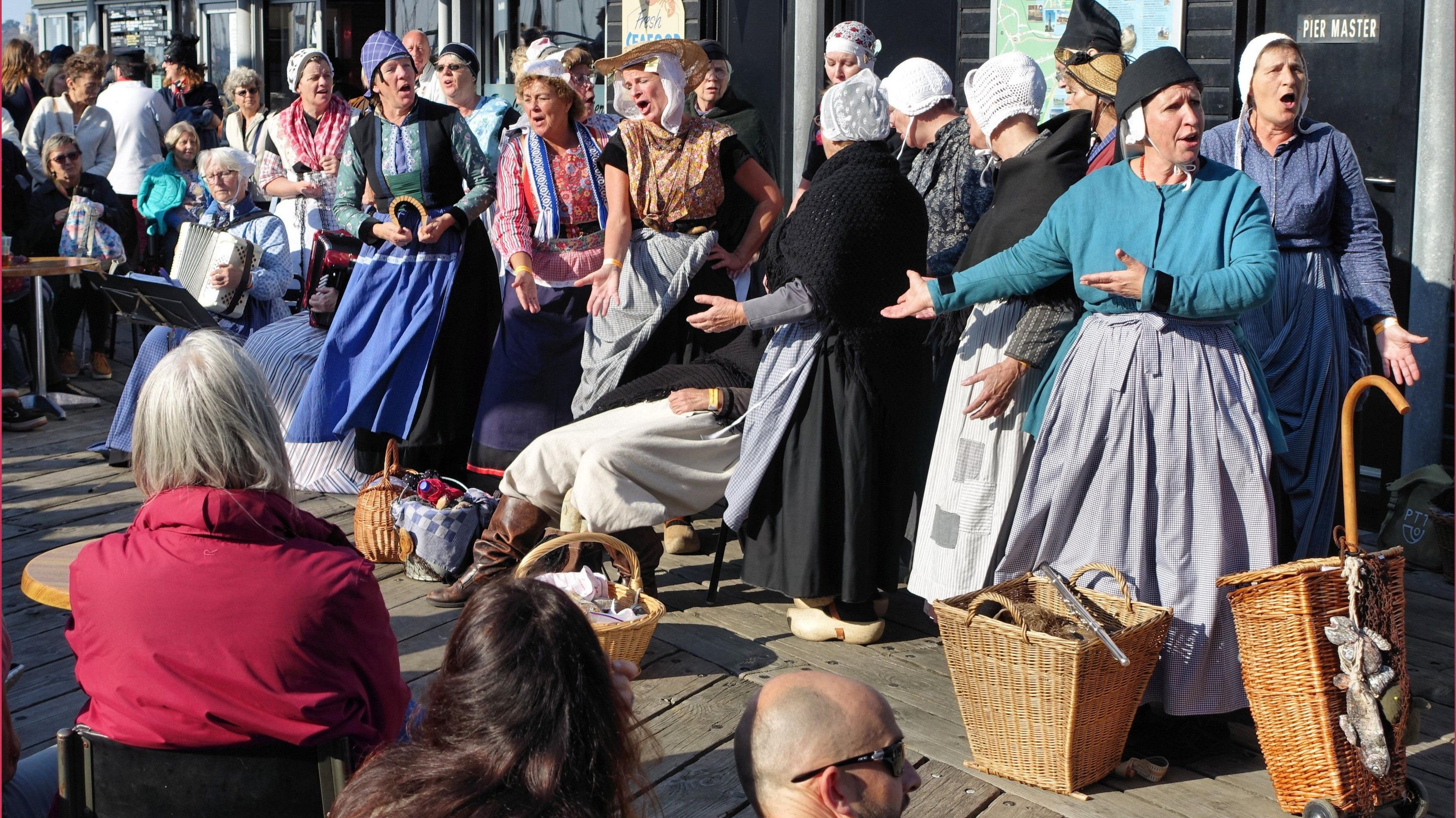 A female choir with about a dozen singers dressed in traditional fishwives costumes from the 1920s