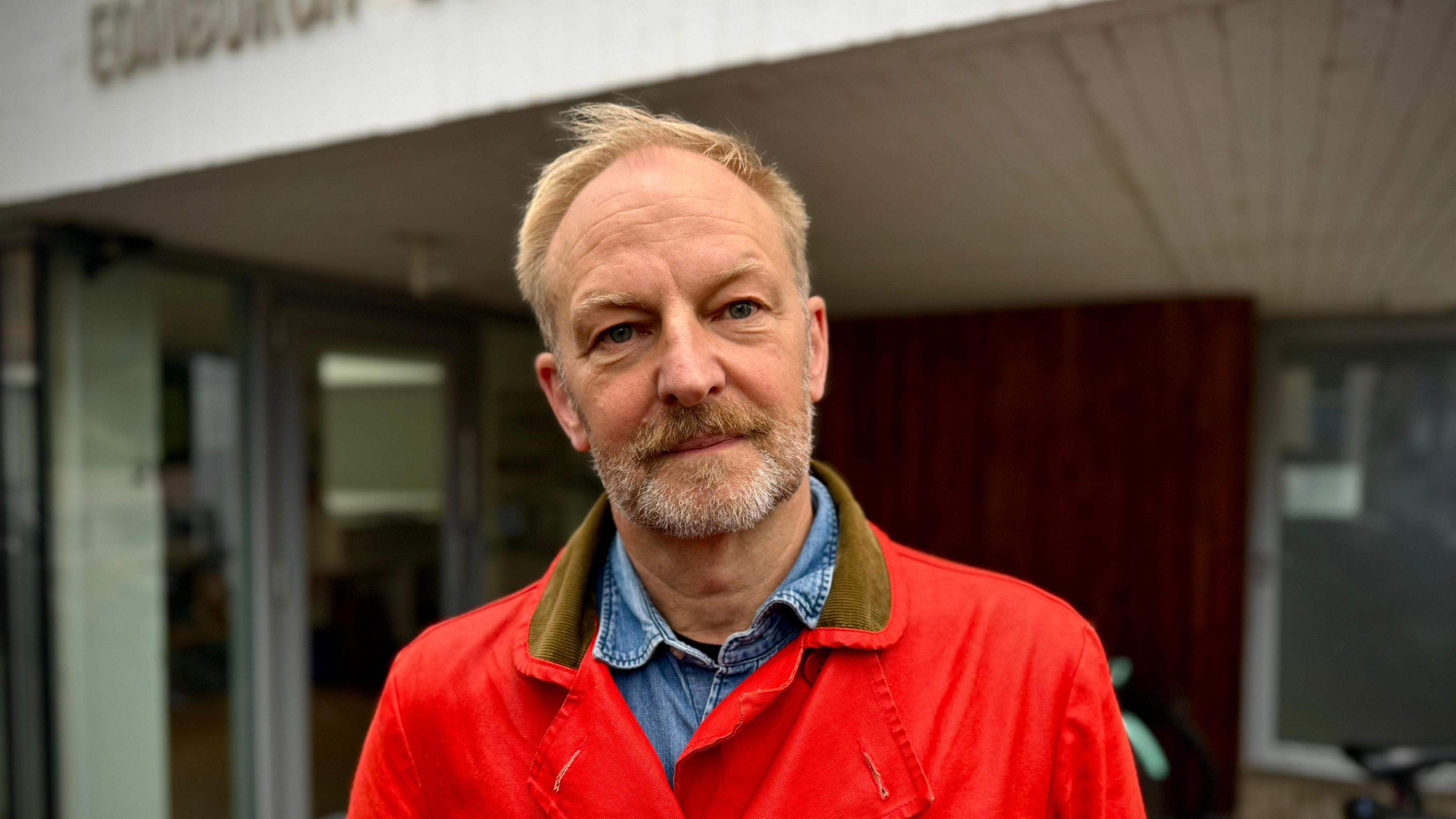 Hans K Clausen wearing a bright red jumper  and a denim shirt