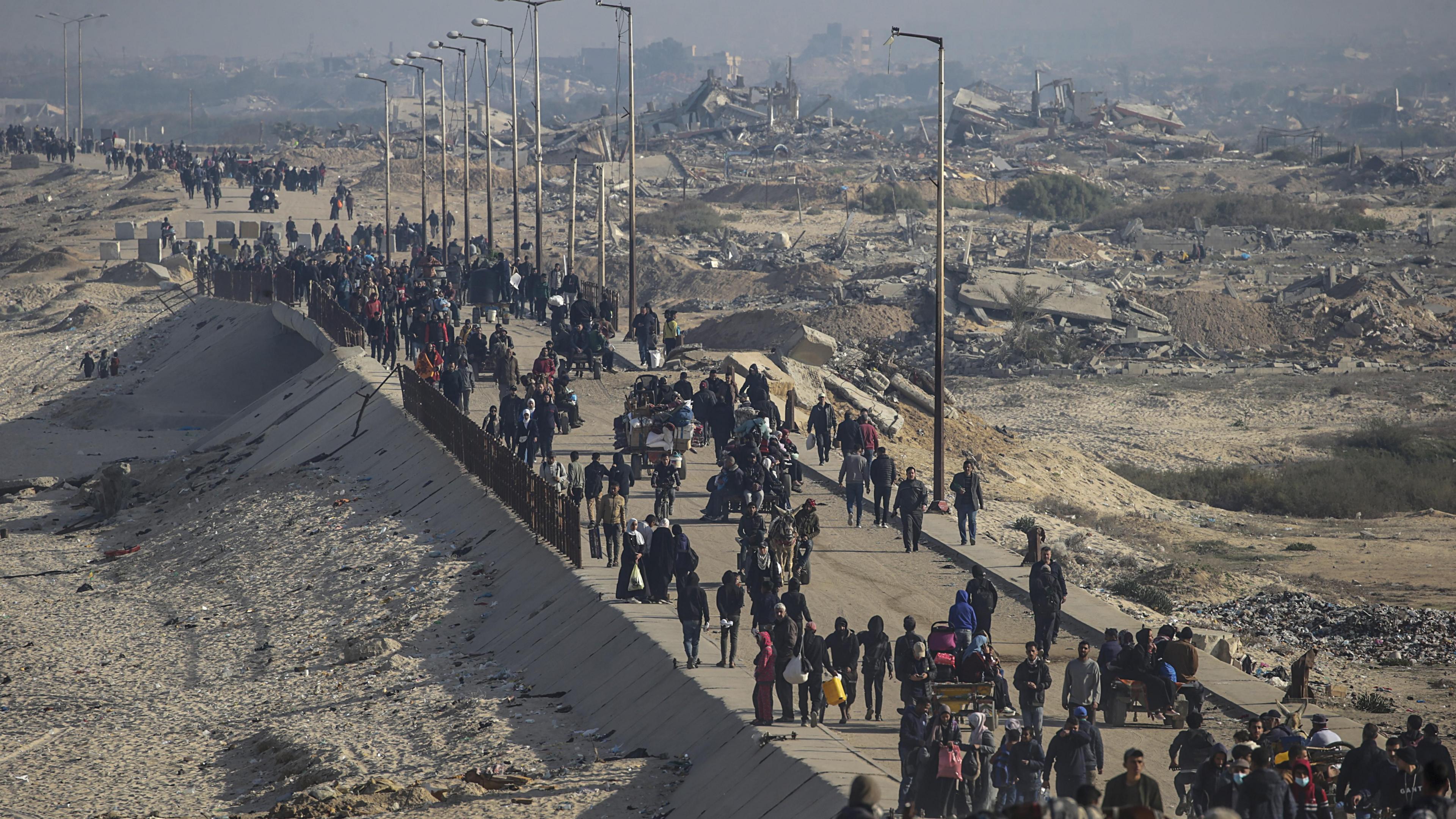 Palestinians make their way along the coastal road in northern Gaza, past the ruins of destroyed buildings (2 February 2025)