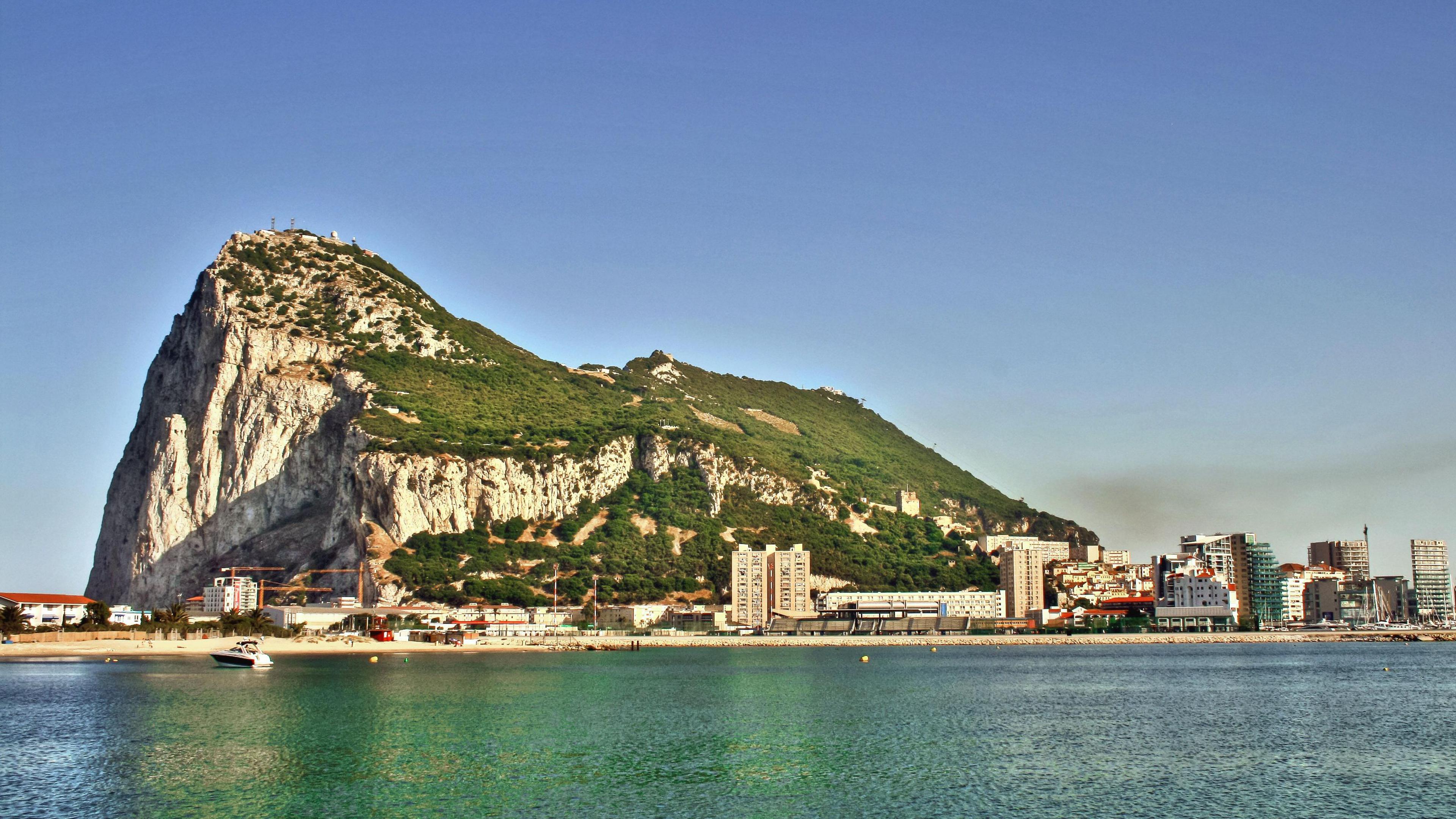 A wide shot of the rock of Gibraltar with the sea in the foreground.