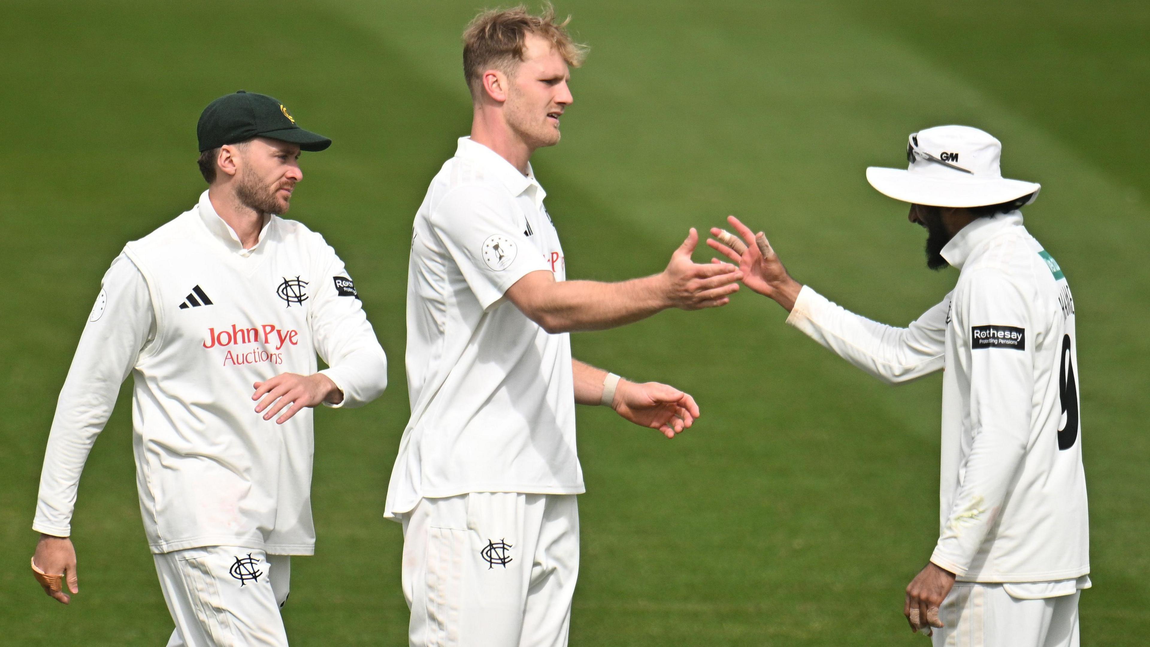 Dillon Pennington (centre) is congratulated by captain Haseeb Hameed (right, wearing a white floppy hat) as another Notts fielder (left) comes towards them