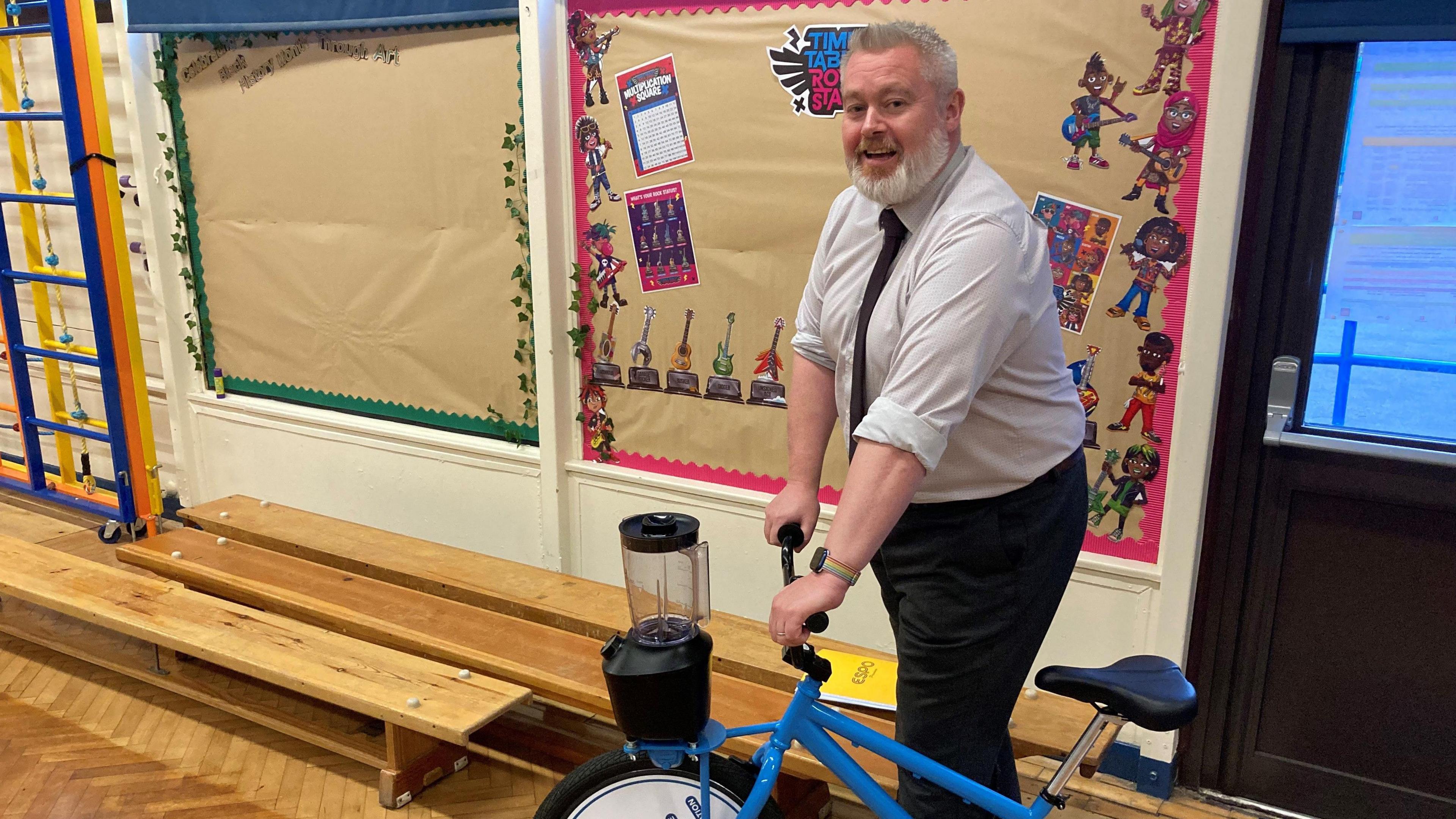 Colin Richardson standing on a bike in a school hall 