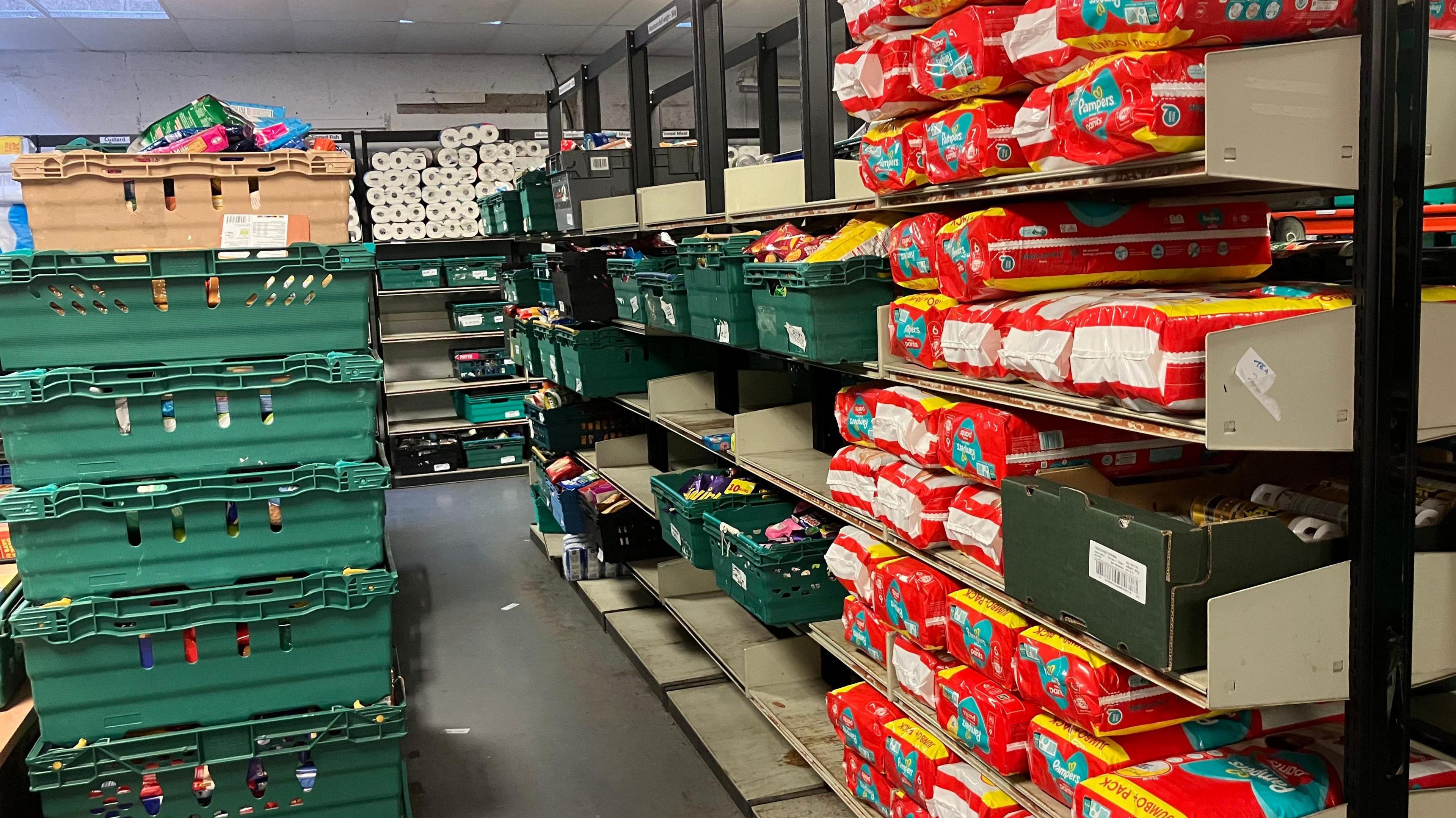 In the warehouse are sturdy shelves reaching right up to the ceiling.  They're holding various items which are then distributed.  They include nappies and toilet roll.