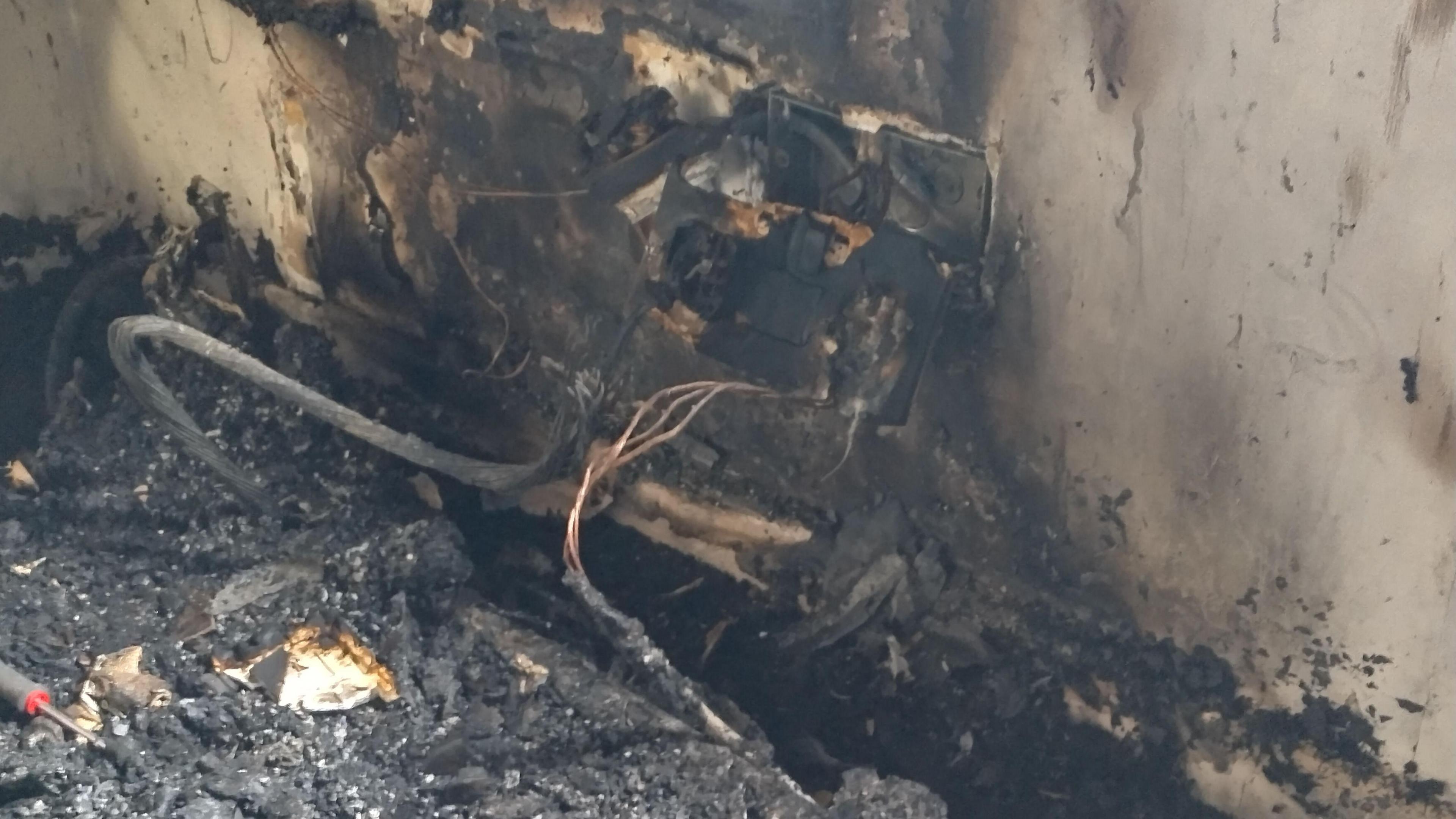 A close-up of a fire-damaged wall, showing a burnt socket