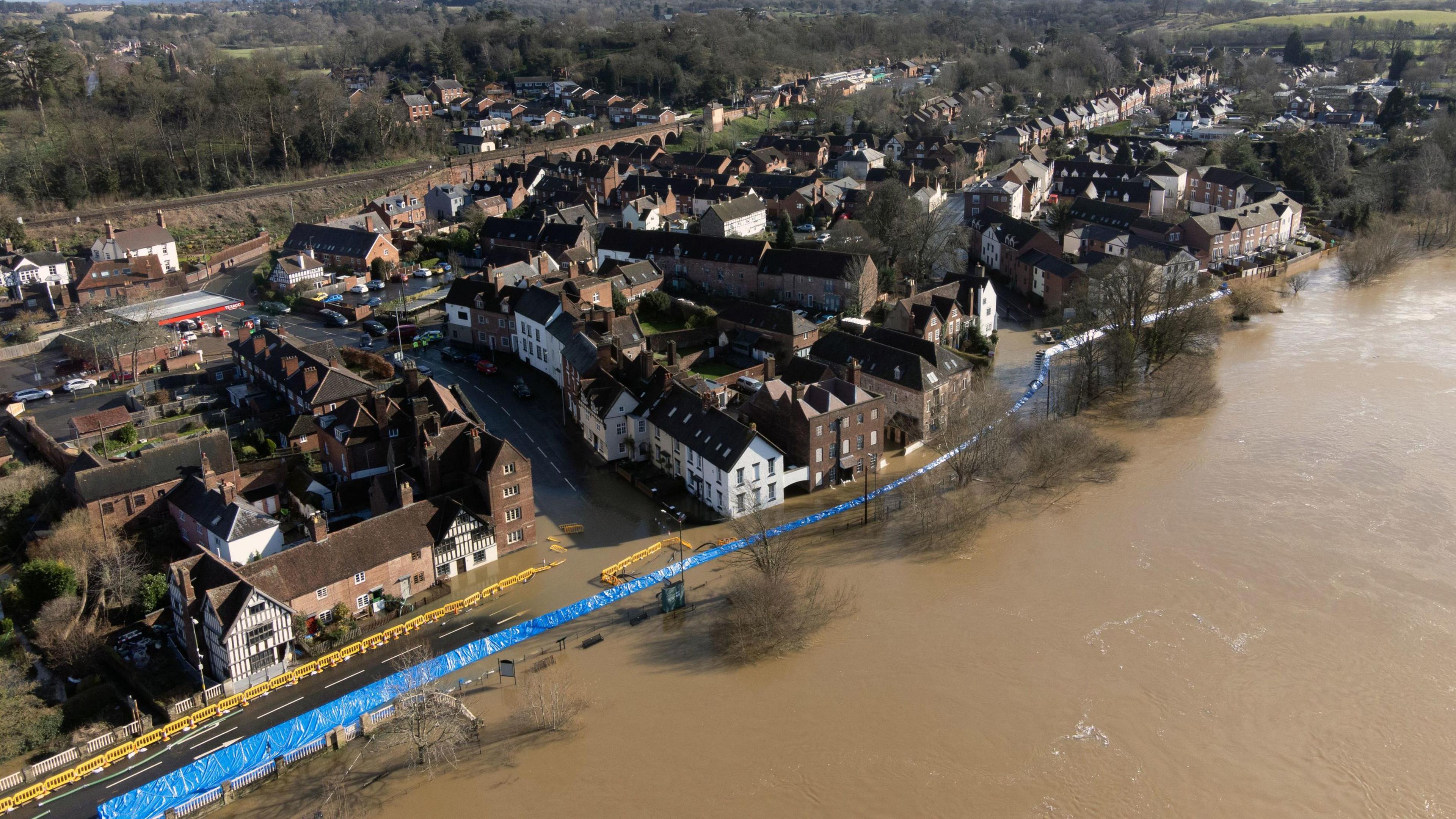 An aerial view of flooding in Bewdley as water from the River Severn breaches the food defences. Water can be seen on the roads next to houses with the blue-coloured flood defences along the river. 