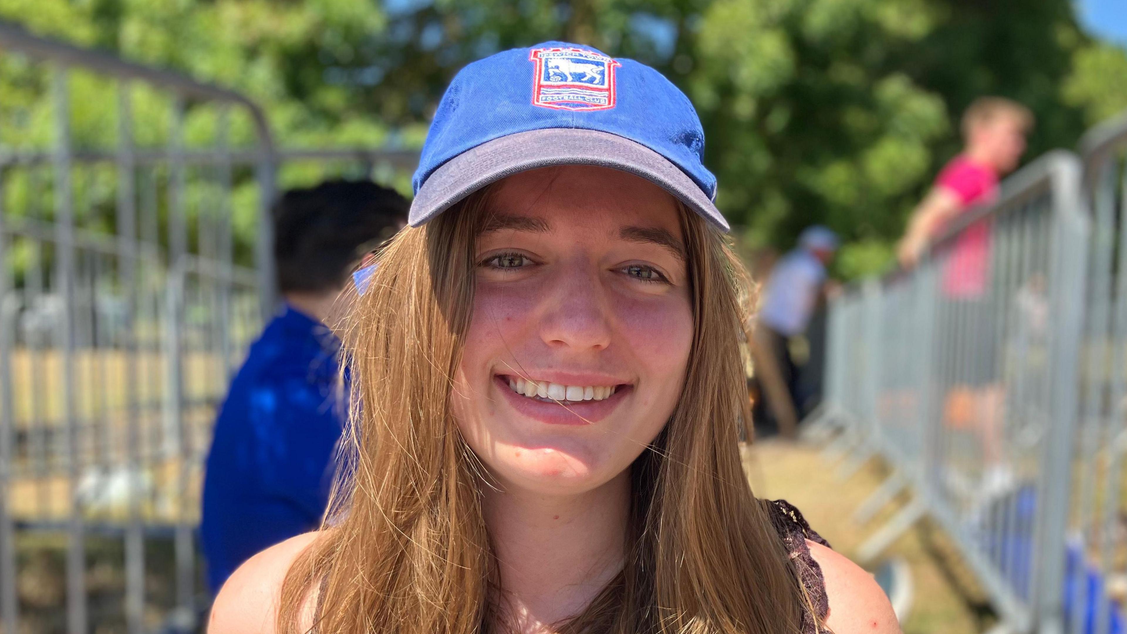 Marlene Krueger smiles at the camera. She wears an Ipswich Town cap and has long brown hair.