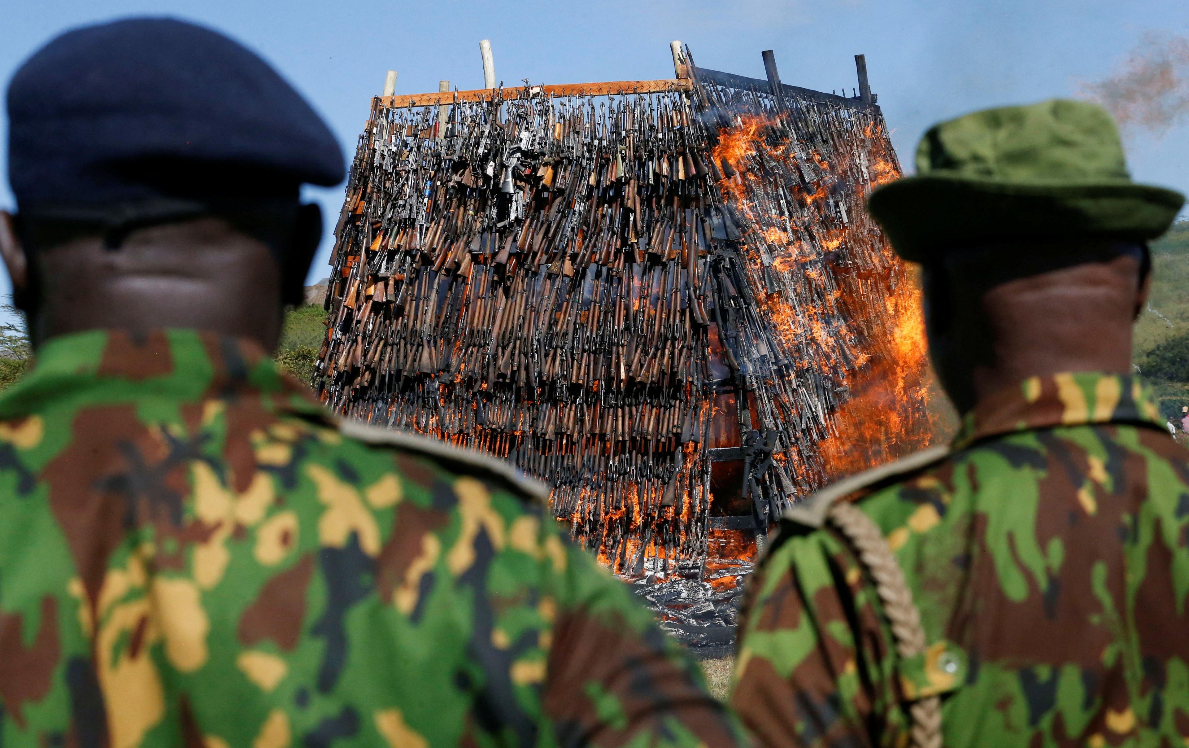 Kenyan police officers watch as a large pyre made up of rifles and other guns is set on fire.