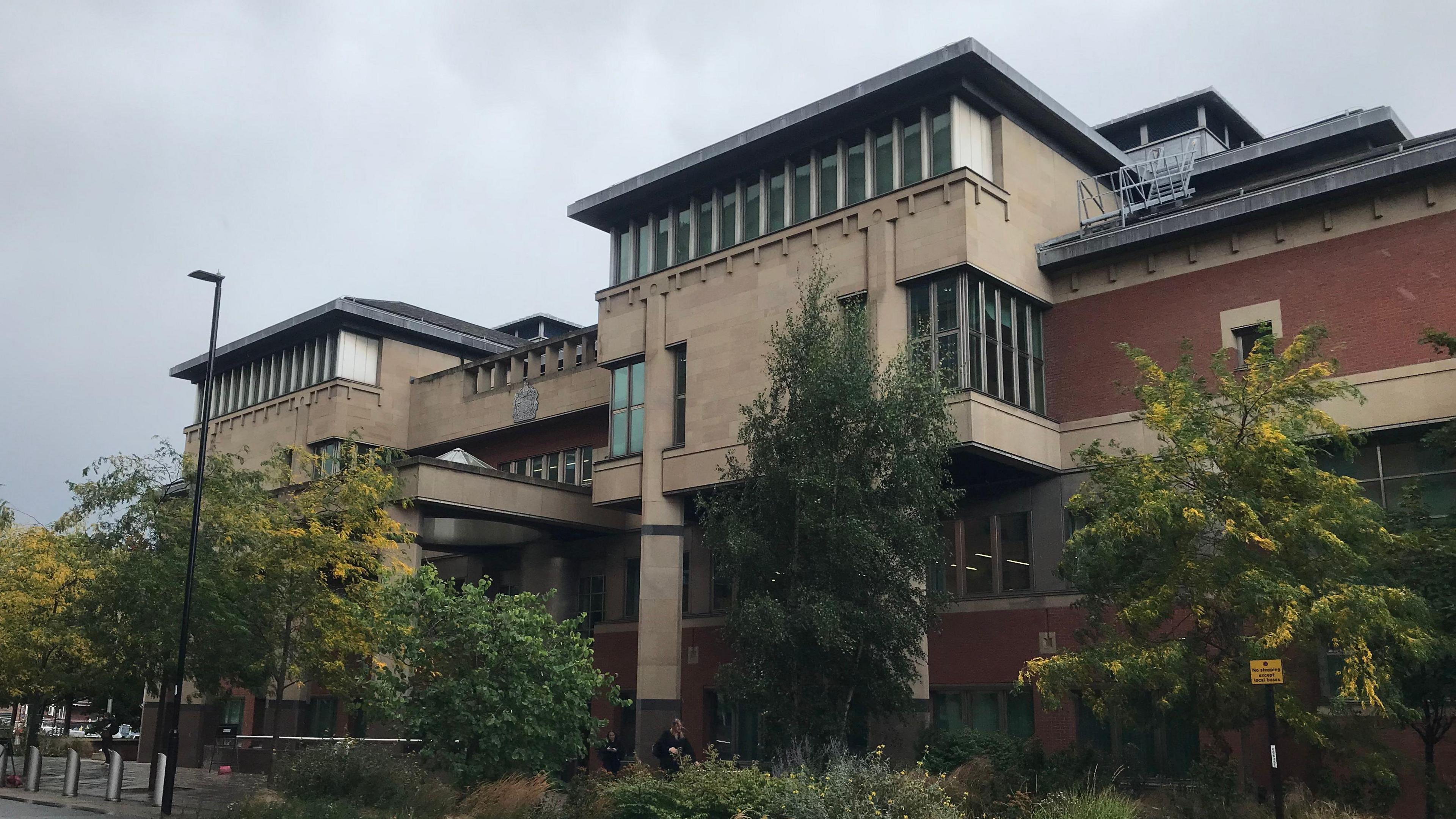 The front entrance to Sheffield Crown Court. Several trees and plans have been planted outside the building.