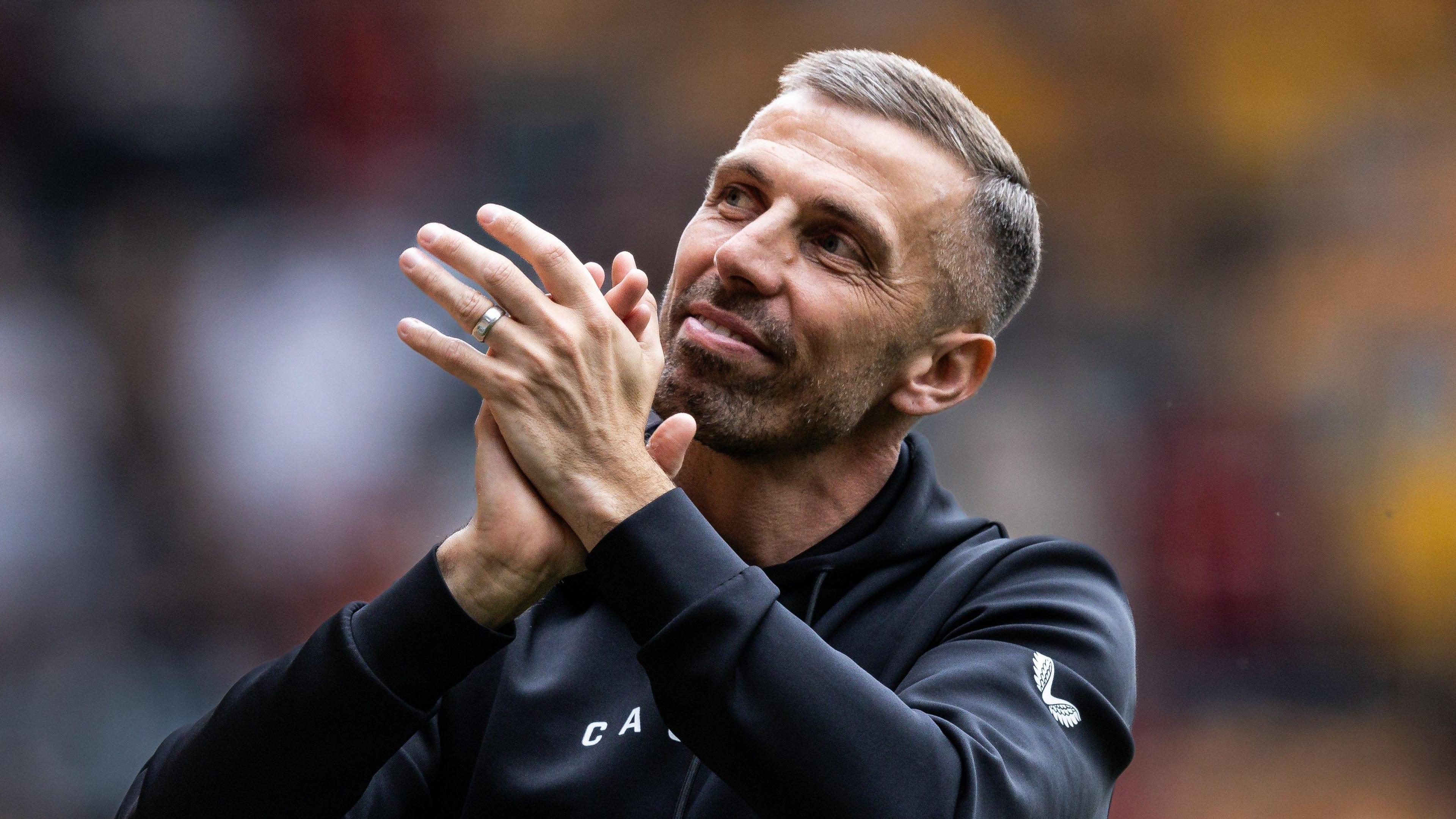 Gary O'Neil, wearing a black Wolves tracksuit, applauds fans