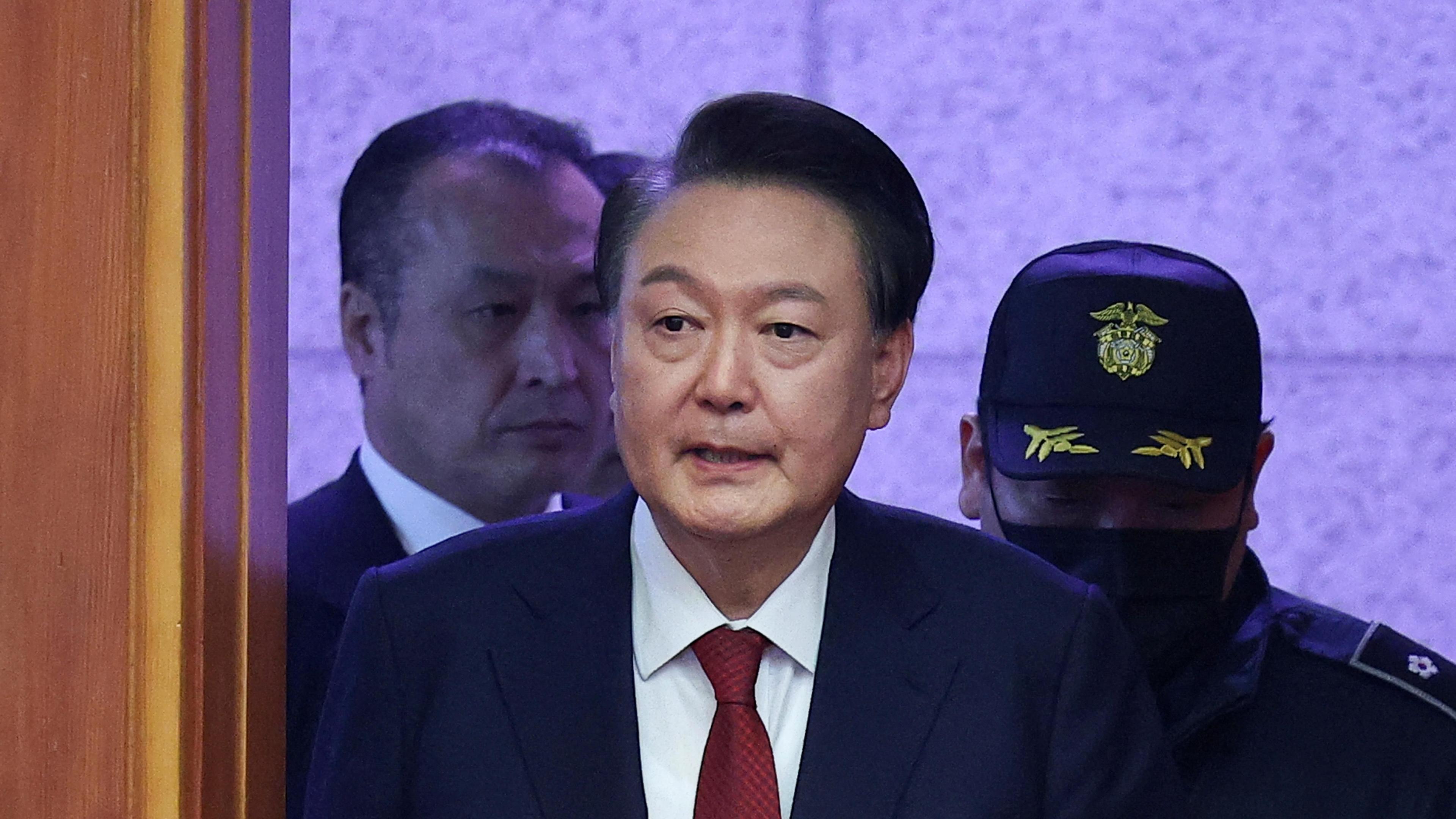 South Korea’s impeached President Yoon Suk Yeol arrives for his impeachment trial dressed in a dark blazer, red tie and white shirt. 