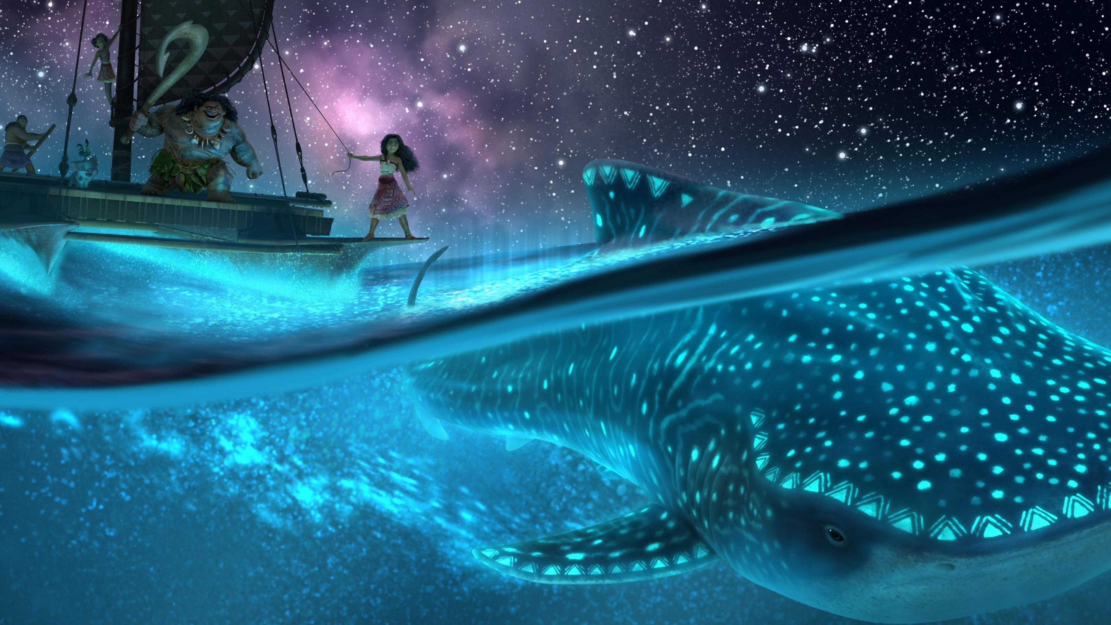 An animated still taken from Moana 2, it shows a night-time scene of the characters sailing on a raft, with a whale underneath in the sea. There are luminous stars and patterns on the whale.